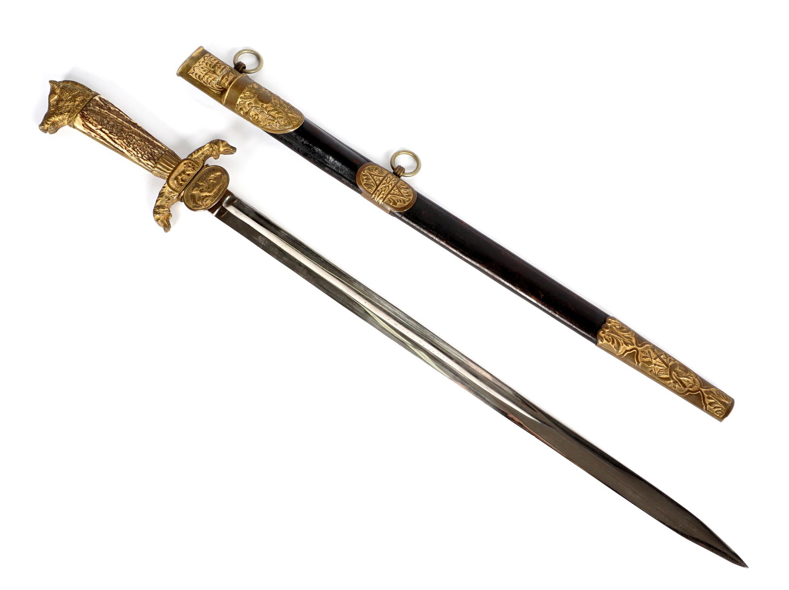 19th Century German Hunting Sword: Cast brass boar head finial, antler grip, cast dog head crossguard with stag in center, cast counter guard with bears. Unmarked blade measures 22.5" long. Leather scabbard with embossed brass mounts,