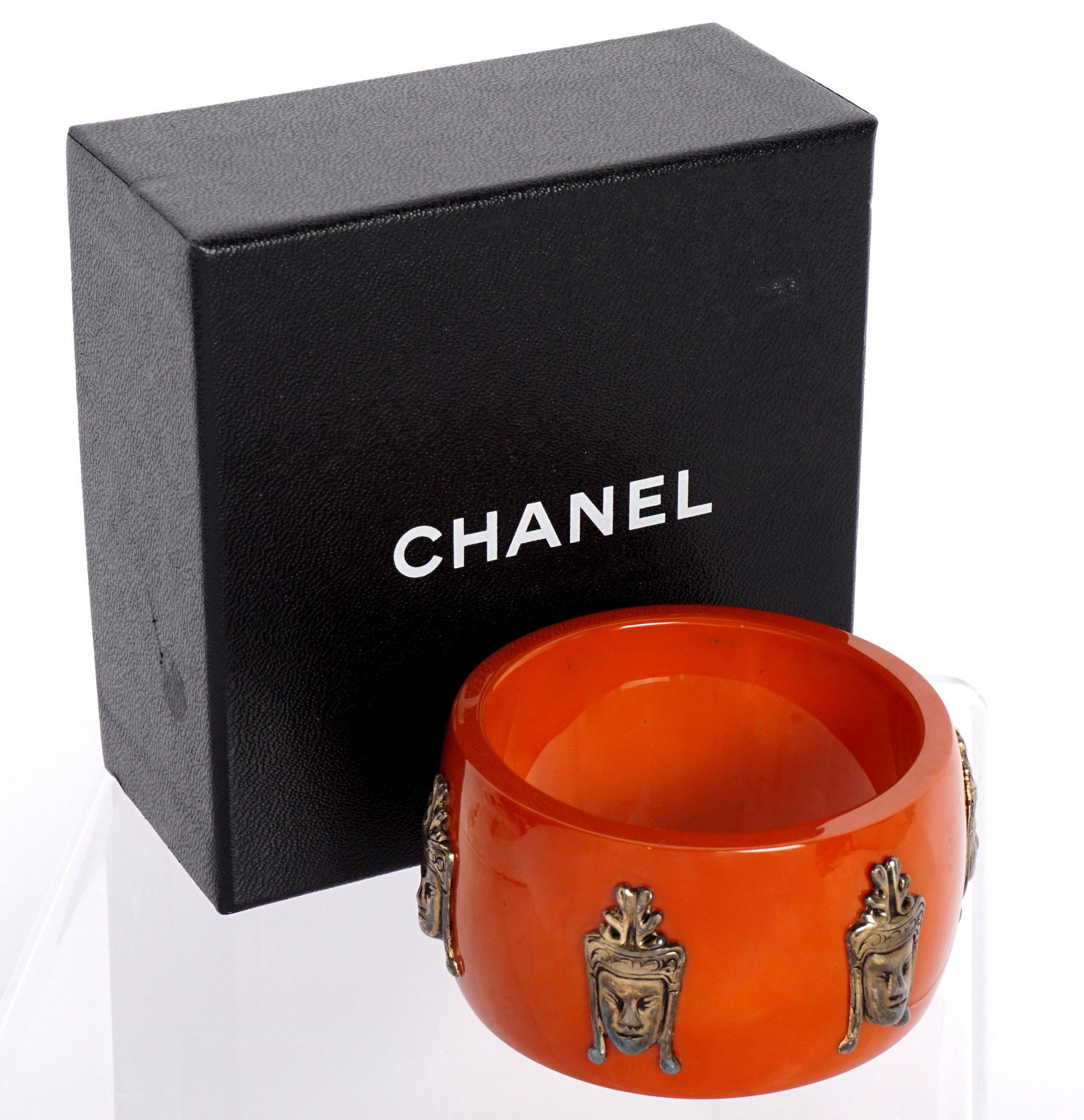 Chanel Orange Cuff Bracelet: Composite orange cuff / bangle bracelet with applied stylized Buddha busts, marked inside, 1.75" x 2.5" interior dia. Sold with a Chanel box.