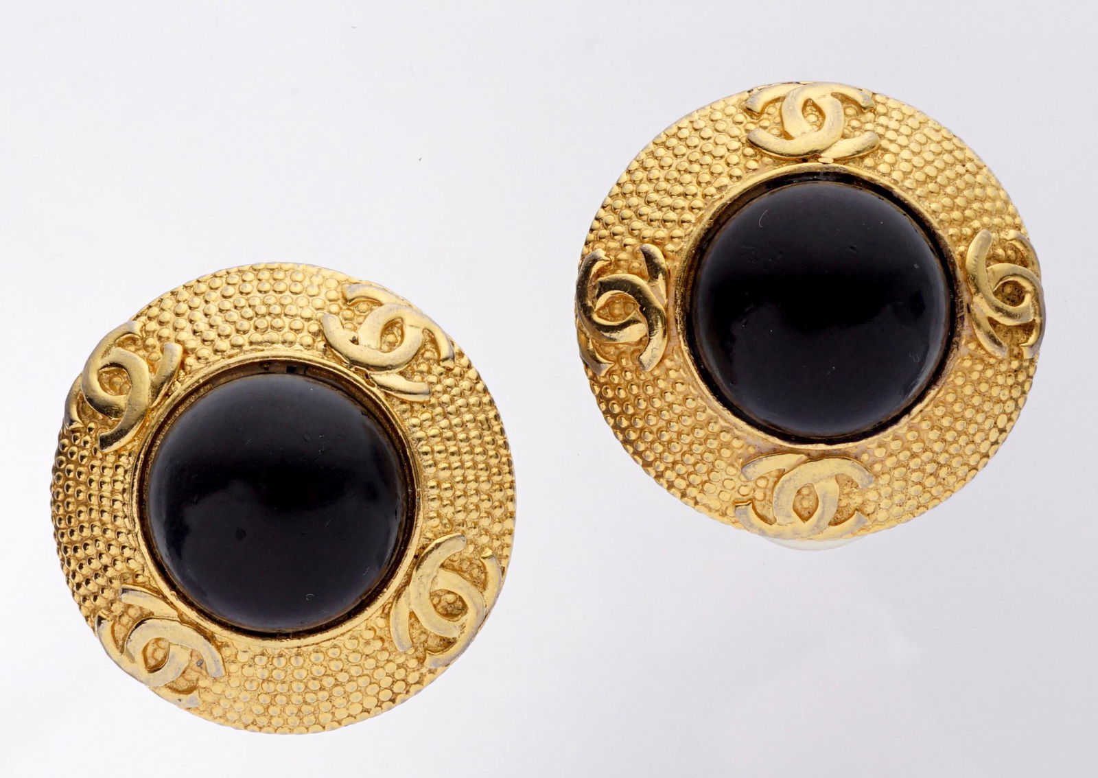 Pair Chanel Vintage Round Ear Clips: Black painted glass cabochon center, gold toned border with logos, 3.5" dia. Flaking to cabochon finish.