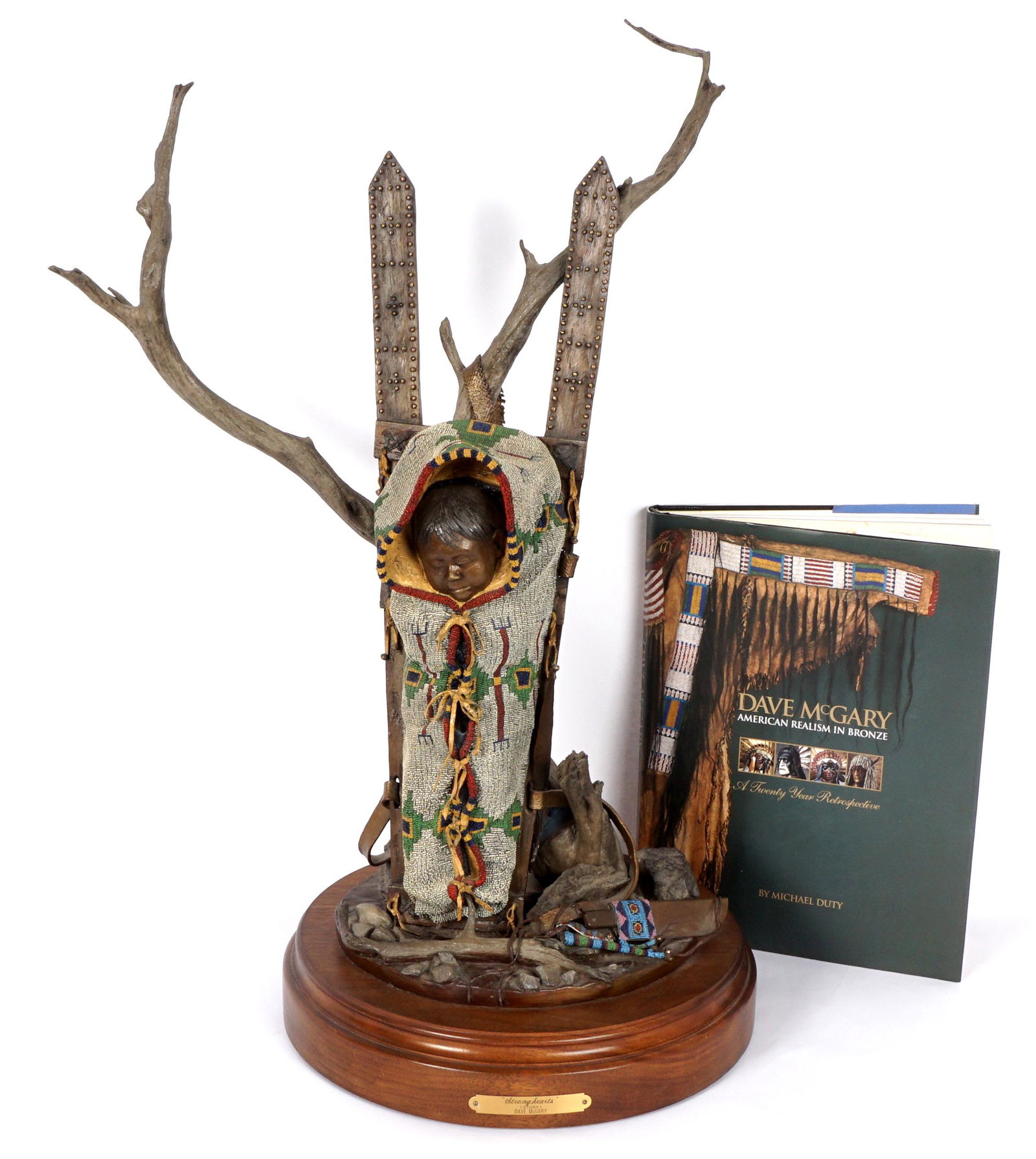Dave McGary Stronghearts Study Bronze: MCGARY, Dave, (American, 1958-2013): Realistic bronze figure of a Sioux baby boy on a beaded cradleboard leaning against a tree with beaded knife below, signed and numbered 17/100, affixed to rotating