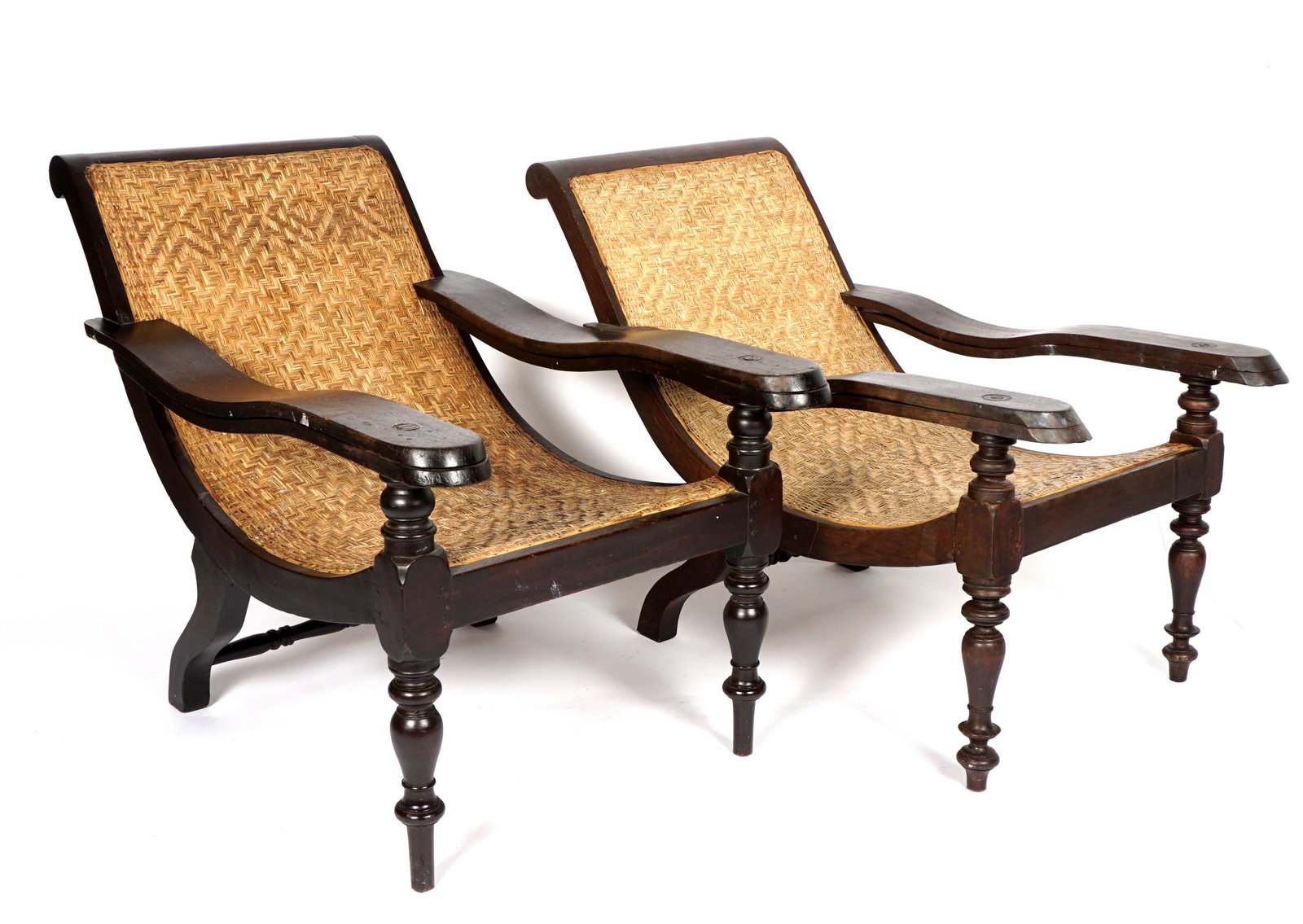 Pair Colonial West Indian Style Plantation Chairs: Mahogany frames, woven slung seat and backs, swivel leg rests, turned front legs, overall 34.25" h. x 28" x 50". Leg rests add another 26". Condition: Wear consistent with age and use.