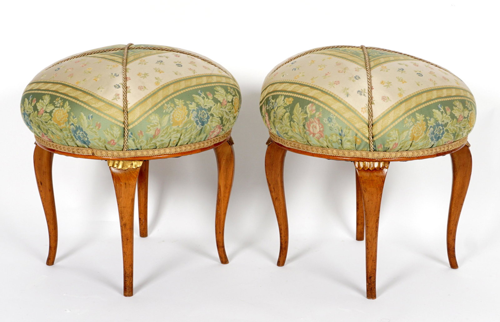 Pair Biedermeier Upholstered Stools: Pillow top foliate upholstered stools, shaped legs with carved gilt wood accents at joints, overall 22" h. x 21" dia.