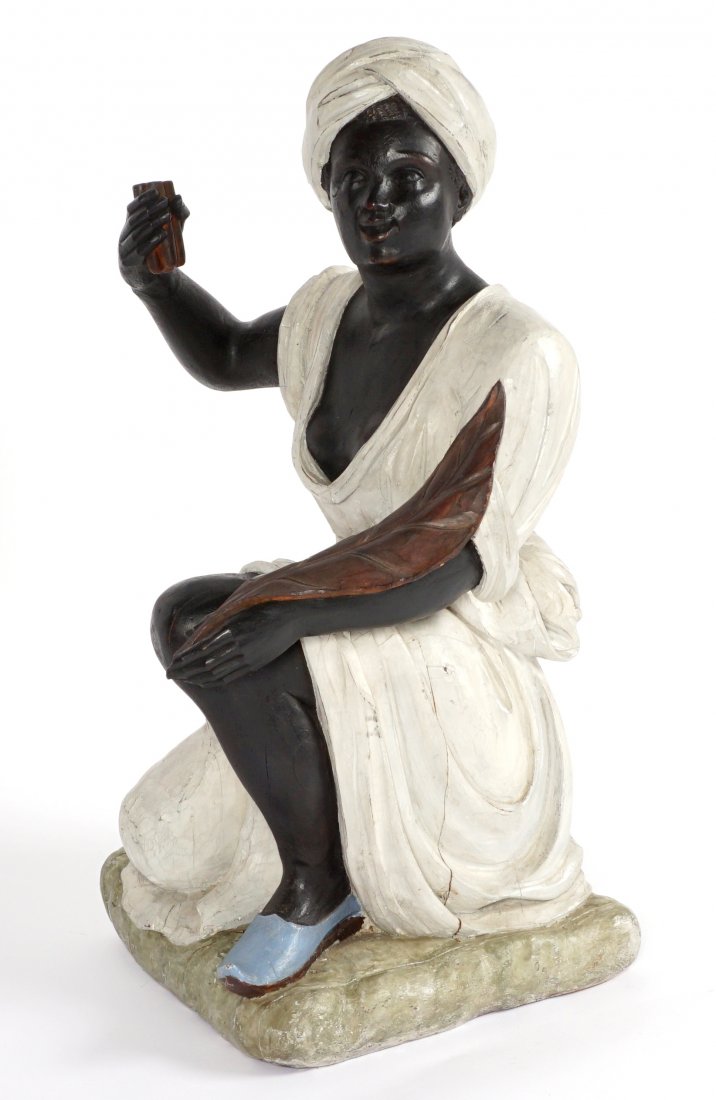 Carved Tobacconist Cigar Store Blackamoor Woman: Carved wood figure of a kneeling blackamoor holding cigars in one hand and a tobacco leaf on the other arm, overall measures 37" h. x 22" x 19". Condition: Wear and chips, age splits.