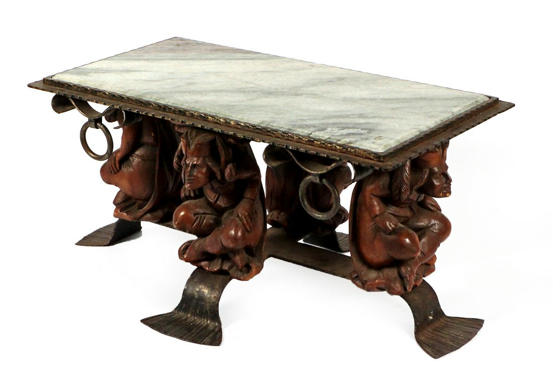 Wrought Iron and Figural Marble Top Coffee Table: Inset marble top, wrought iron frame and rings supported by four figural carved wood figures, on shaped iron paddle feet. Overall 19.25" h. x 39" x 21".