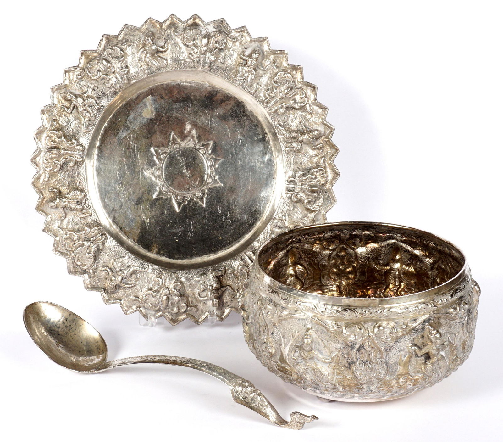 Burmese Silvered Repousse Bowl & Underplate: Three pieces total to include matching bowl and underplate with alternating dancers and foliate reserves. Bowl on three ball feet measures 4.75" x 9", tray on three ball feet 1.75" x 13". Sold with a
