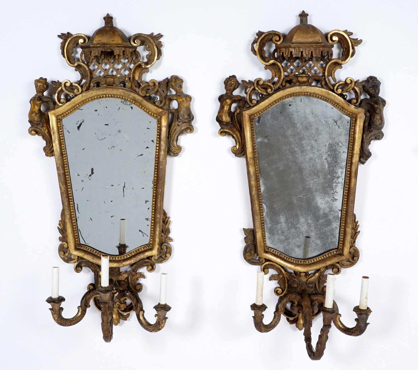 Pair 19th Century Italian Gilt Mirrored Sconces: Rococo style gilt wood and plaster framed, canopy crest, figural winged maidens at shoulders, foliate scroll and lower crest. Electrified 3 scroll arms, overall 42" h. x 20.5" x 10" . Condition: Spott