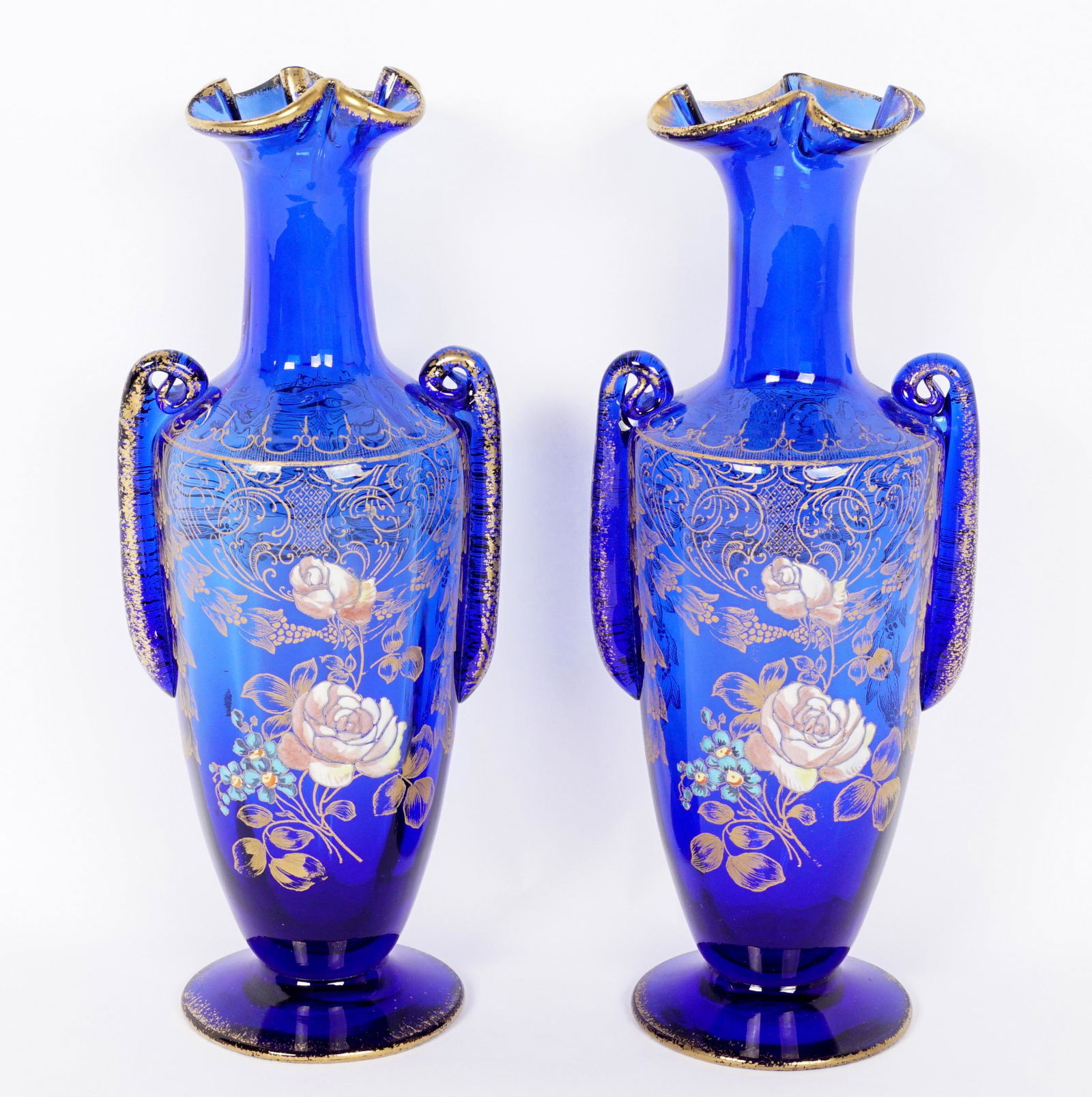 Pair Moser Cobalt Glass & Enamel Vases: Each with folded in rim, enamel floral decoration with gilt accents, polished pontil, number 24 on foot of one. Measure 11" h. x 4.5".