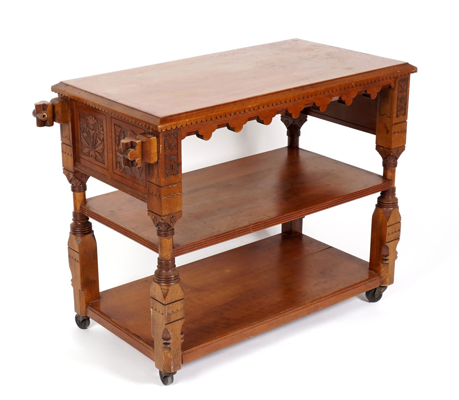 Attrib. Daniel Pabst Three Tier Dumb Waiter: Carved walnut three tier dumb waiter, rectangular top over carved trim and under skirt. Turned and blocked supports, carved floral motif panels, all on castors, 30" h .x 39" x 20". Condition: Missing