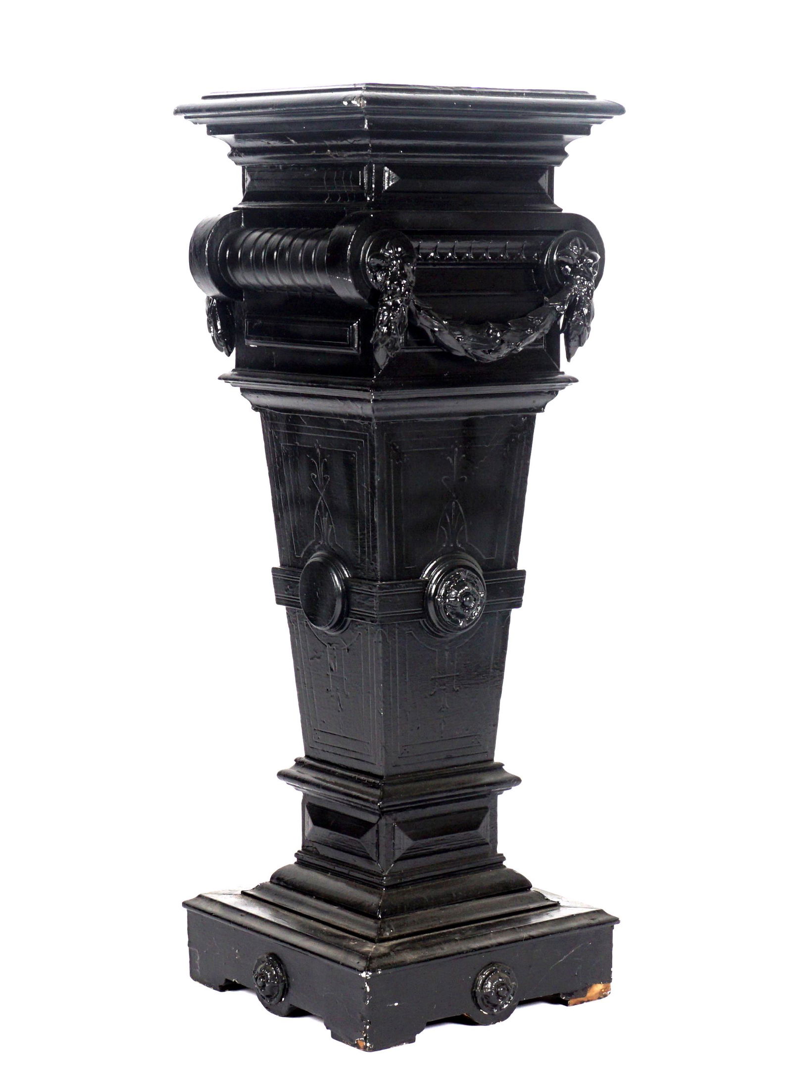 Ebonized Aesthetic Movement Pedestal / Plant Stand: Square top, carved and tapered body with applied decoration and foliate swags, square base. Overall 40.5" h. x 14.5" x 14.5". Condition: Chips to finish, veneer loss at base.