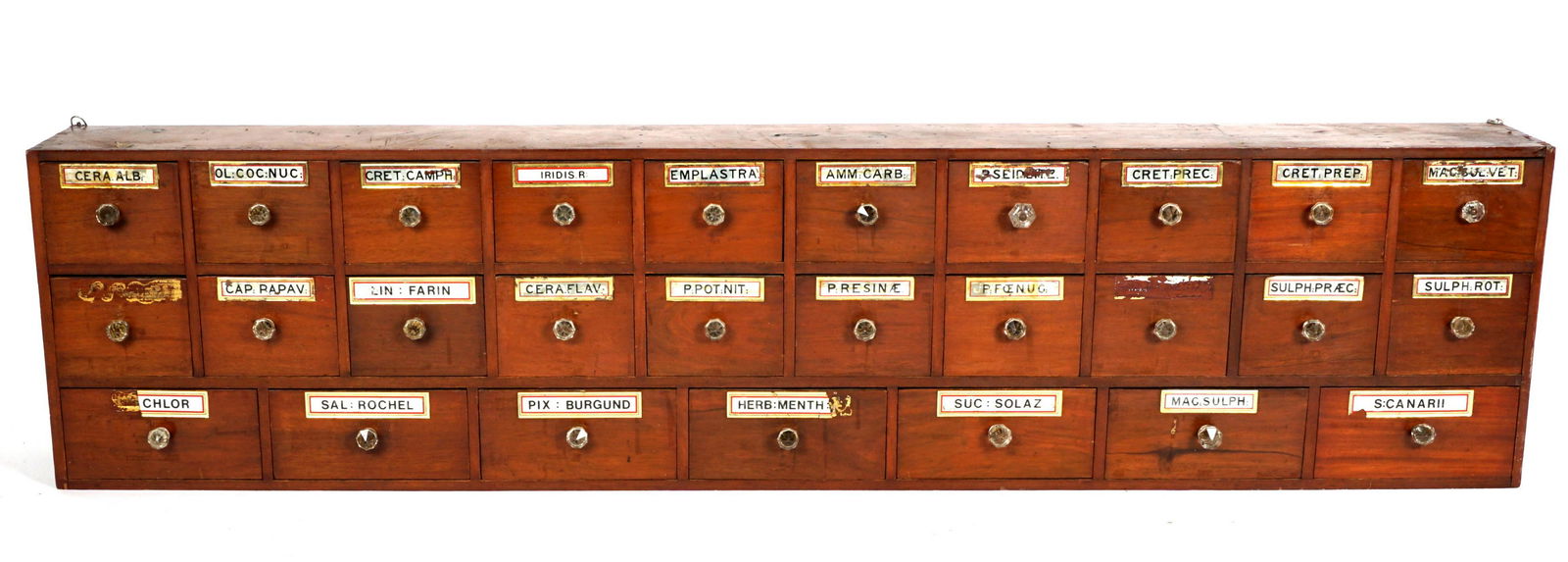 Late 19th C. 27 Drawer Apothecary Cabinet: 27 drawers, each with reverse painted glass labels, glass pulls, overall measures 37" h. x 58.5" x 12". Condition: Loss of paint to multiple plaques, other wear consistent with age and use.