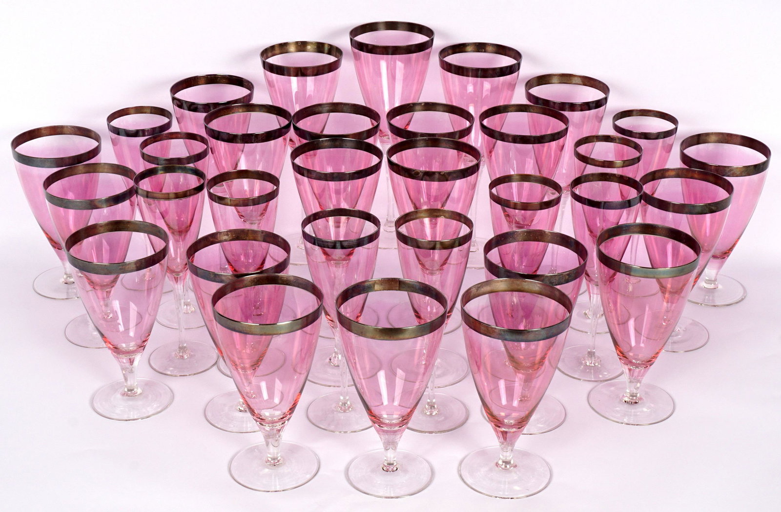 32 Pink Venetian Glass Stems with Silverplate Rims: 32 pieces total, pink glass bodies, clear glass foot, silverplate rims, to include 11 wine glasses (8.25" h.), 11 white wine (6"), 10 water goblets (7"). Tarnish to rims.