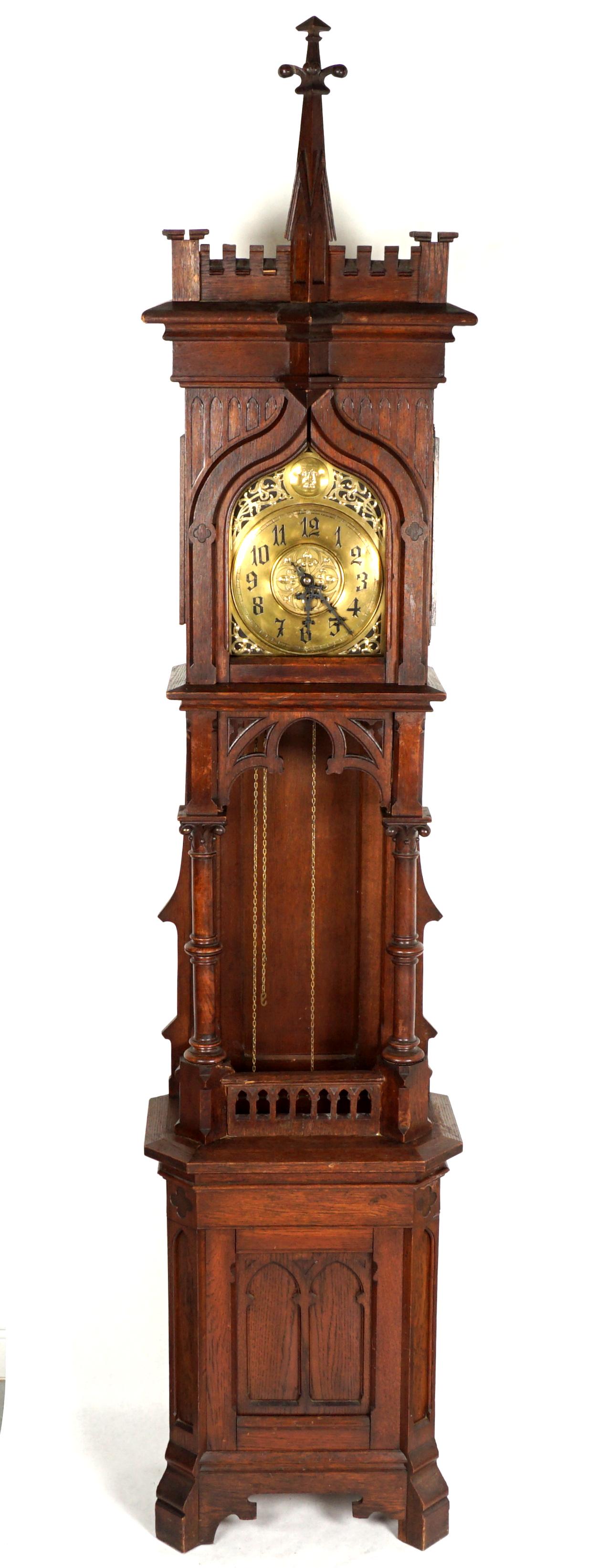 C. Jupitz Gothic Revival Tall Case Clock: Castle motif architecural crest, bonnet with arched open front window, mesh side panels. Open top trunk with full columns, pierced valences. Lower trunk with carved decoration, on four feet. Pierced b