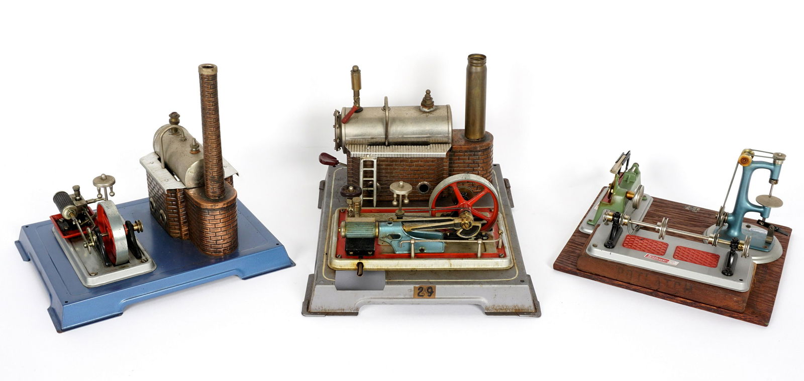 Two Vintage Wilesco Steam Engines and Accessories: Three pieces total to include 1) Wilesco steam engine, metal base, overall 7.5" h. x 12" x 9.75". 2) Wilesco steam engine, metal base, 9.75" h. 10.5" x 8". 3) Work station with drive shaft, drill pres