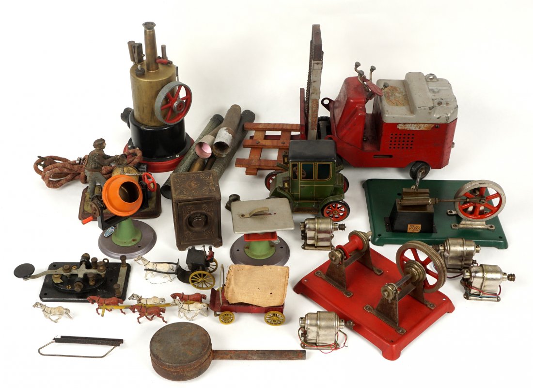 Collection of Steam Engine Accessories and Toys: An assorted collection of model vintage steam accessories and parts to include spare stacks, spare flywheels, Wilesco cement mixer and table saw, Becker tin painted winemaker, three generators, and mo