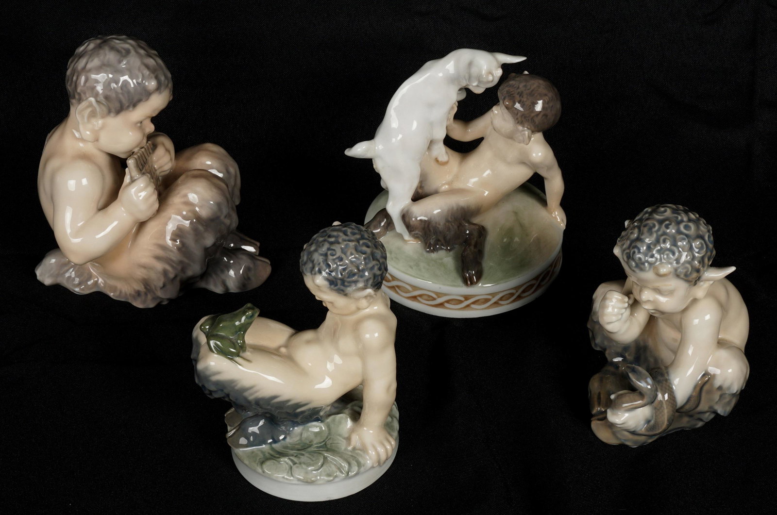 Four Royal Copenhagen Porcelain Pan Figures: Four pieces total to include 1) Pan and the Billygoat, #1012, 5" h. x 4.5". 2) Fawn with a frog, #1713, 4.75" x 3.75". 3) Pan playing the flute, #1736, 5.75" h .x 4.25" x 5". 4) Fawn with a snake, #17