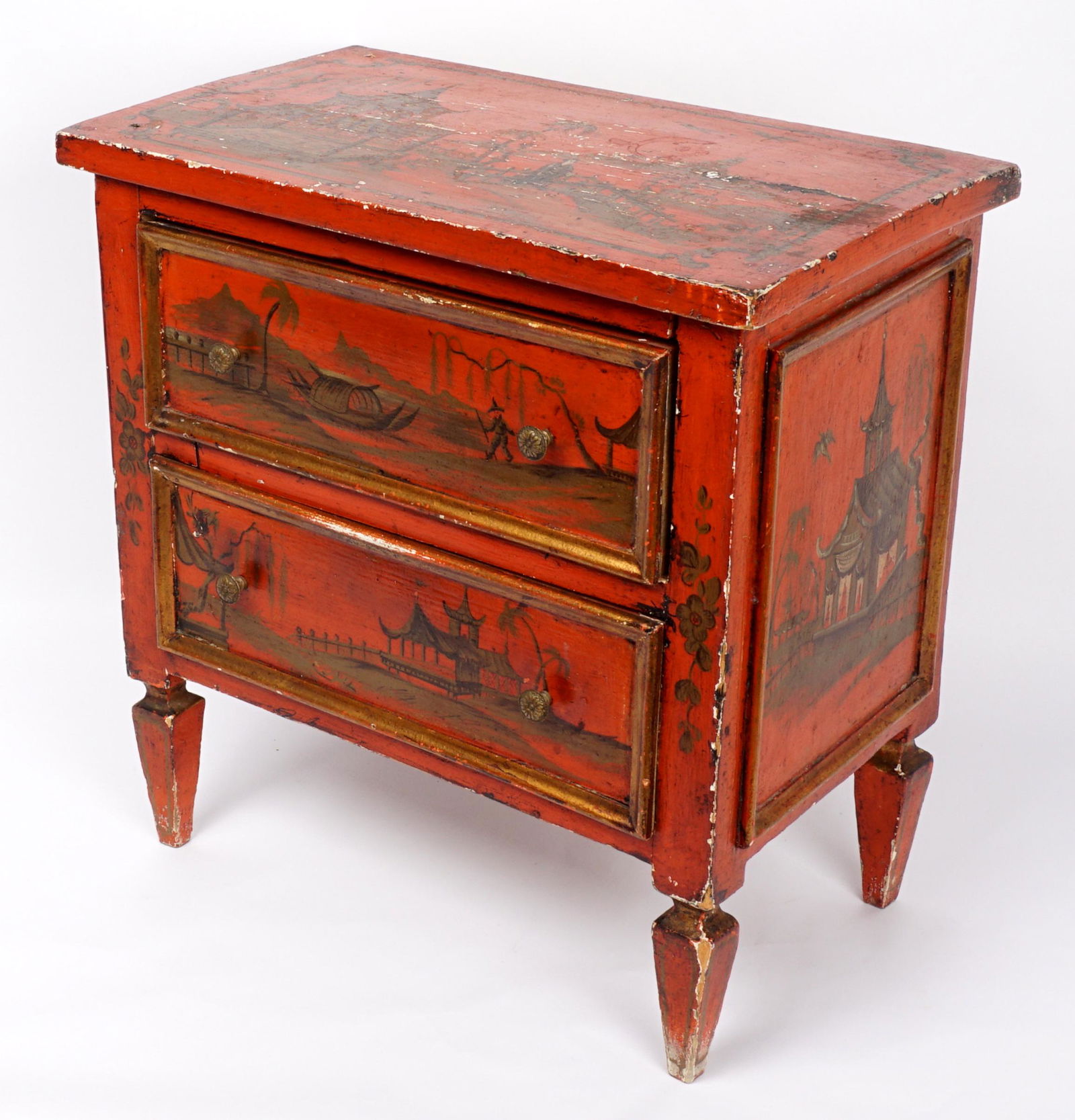 Miniature Chinoiserie Decorated Two Drawer Chest: Red ground chinoiserie decorated with outdoor genre scenes, two drawers, tapered legs, 18" h. x 18" x 10.25". Condition: Chips and loss to decoration.