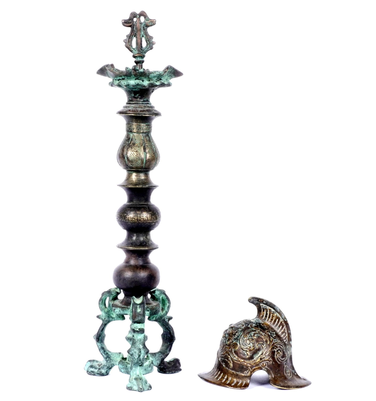 Miniature Bronze Helmet and Bronze Candlestick: Two pieces total to include 1) French design miniature bronze helmet, lion mask and foliate decoration, raised spine, unmarked, 3.75" h. x 5" x 3.5". 2) Middle Eastern style bronze candlestick form de