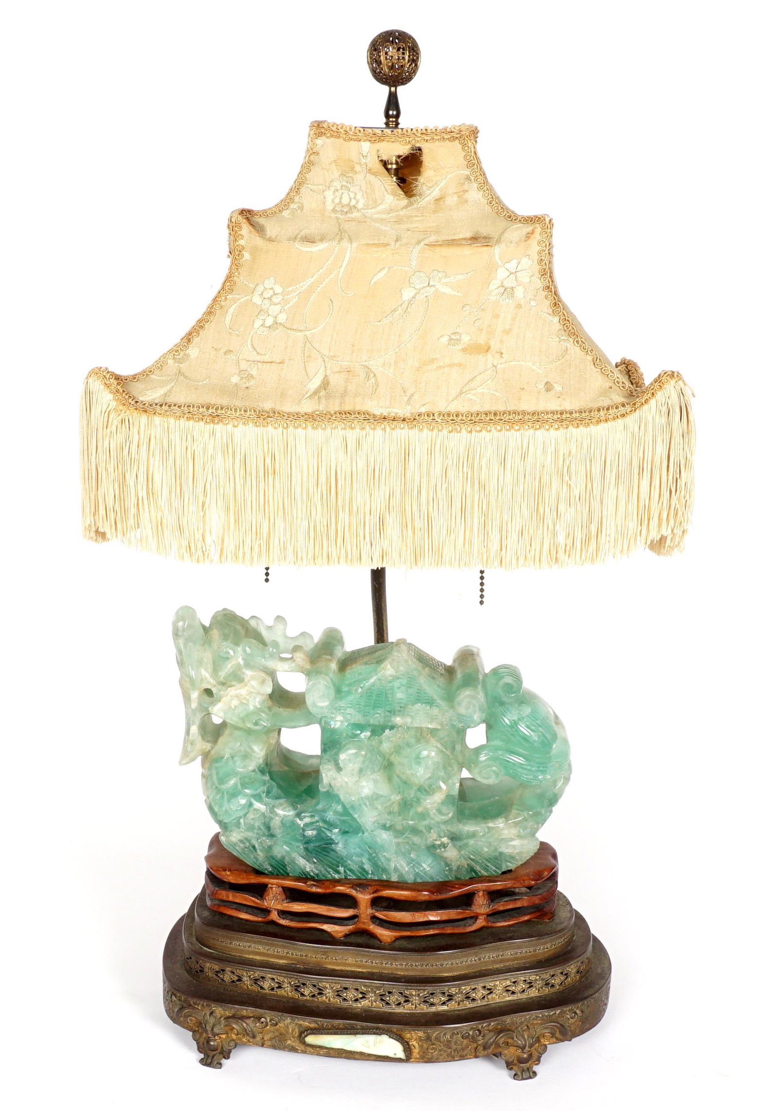Chinese Carved Green Quartz Dragon Lamp: Green quartz figural dragon with figures, 6.5" h. x 9.25" x 3.75". Fitted wood and stepped pierced metal base, single lower socket, double upper sockets, silk pagoda form shade in disrepair. Overall 2