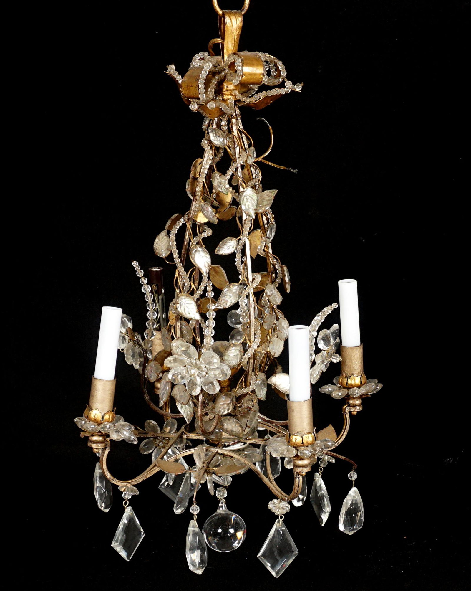 Attrib. Maison Bagues Brass and Crystal Chandelier: Four arm iron frame, gilt brass and molded glass leaves and petals, crystal swags, prism drops, and center ball finial. Overall 27" h .x 17". Condition: Chips and missing crystals. uneven finish.