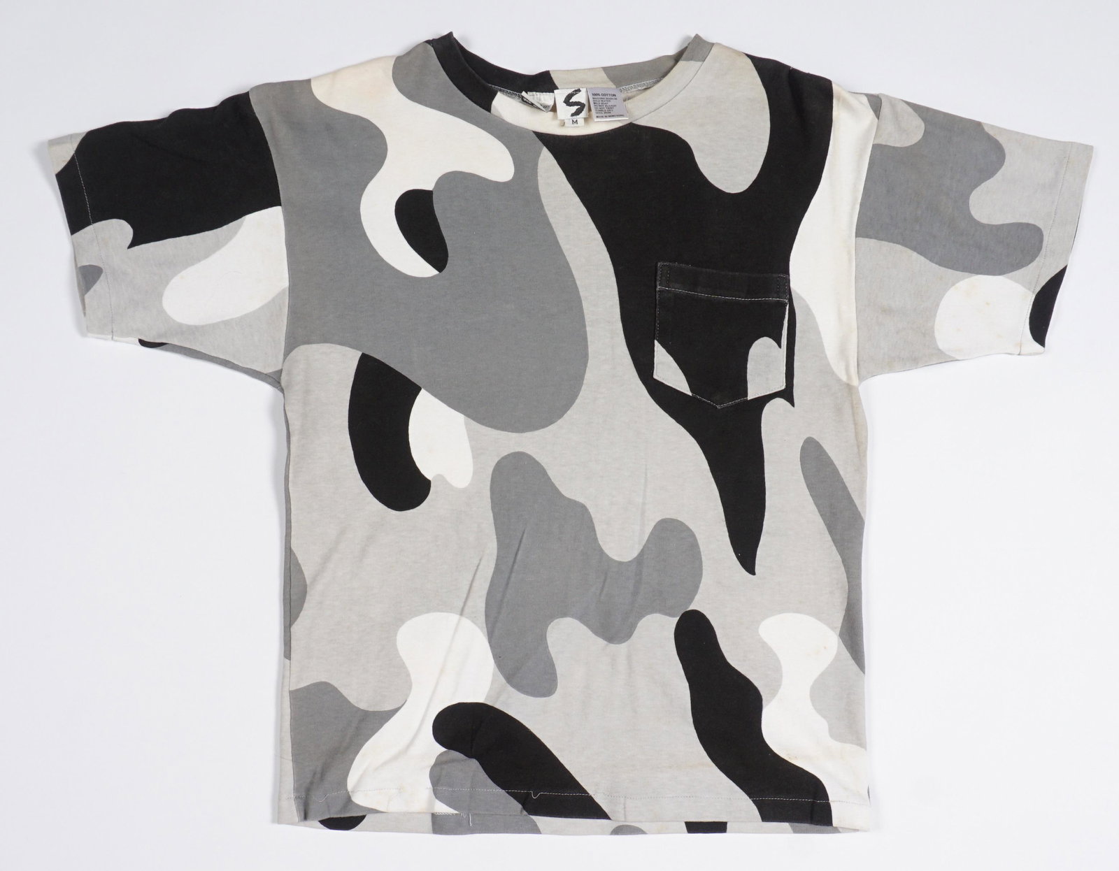 1987 Stephen Sprouse Andy Warhol Camouflage Shirt: Black, grey, and white tee shirt with pocket, designed by Stephen Sprouse, labeled with 1987 Estate of Andy Warhol tag as well. Size Medium. Condition: Wear, could use a proper cleaning.