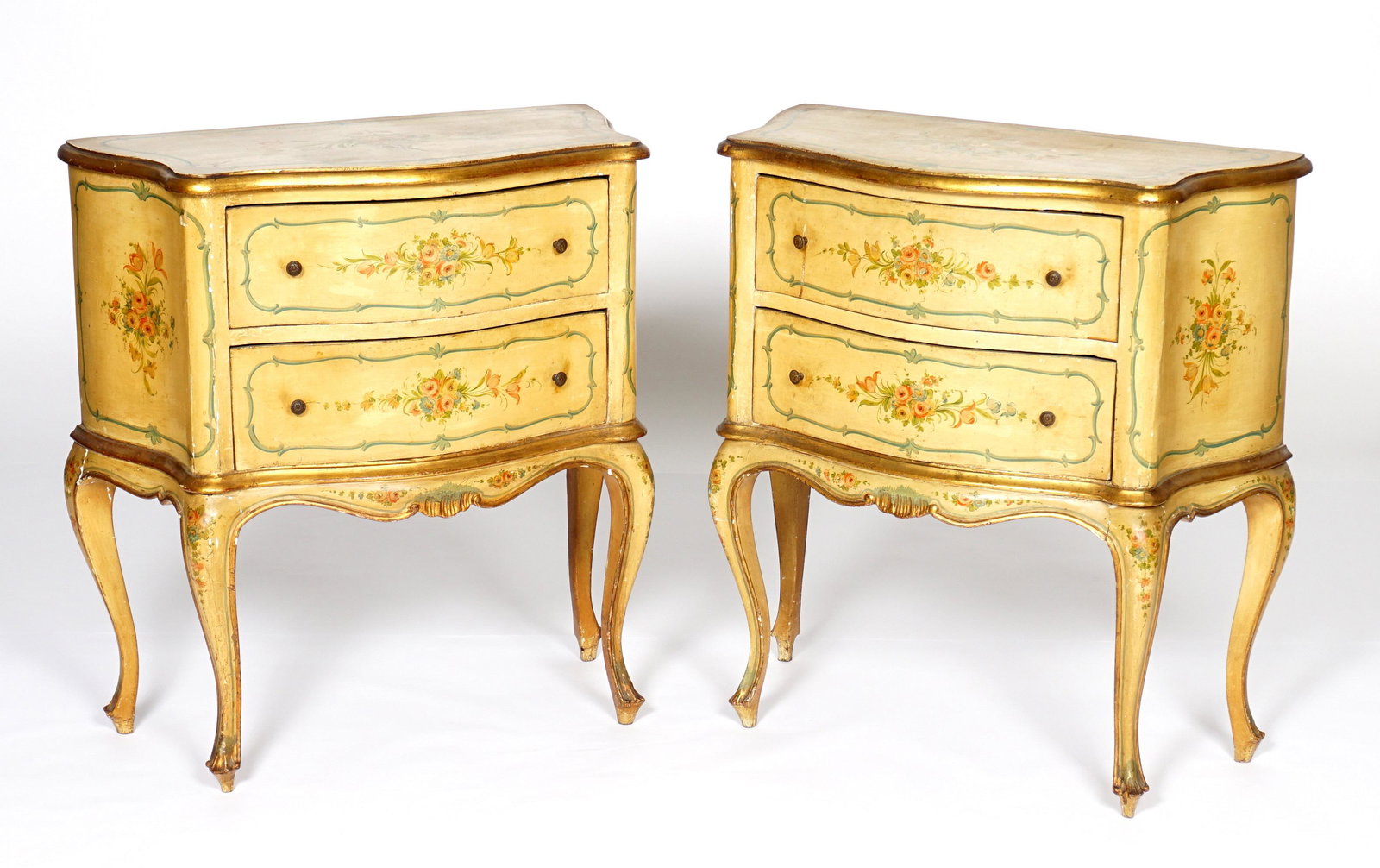 Pair French Paint Decorated Commodes: Floral paint decorated all over, serpentine top with conforming two drawer base, carved and shaped skirt, shaped legs. Overall 31.5" h. x 29.5" x 15". Condition: Wear to paint decoration.