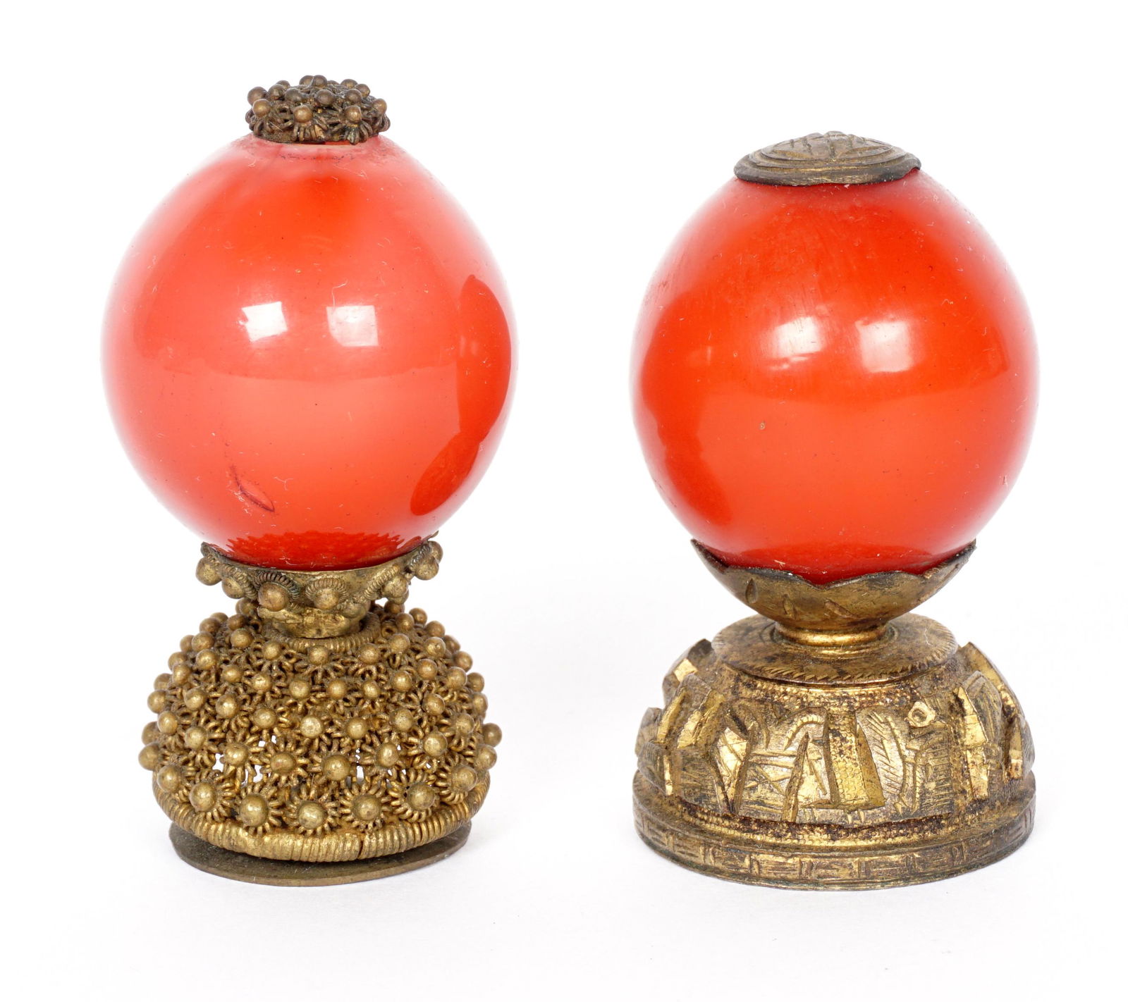 Two Chinese Qing Second Rank Hat Finials: Each with red Peking glass globes, one with pierced floral base, the other with raised decoration. 2.5" h.