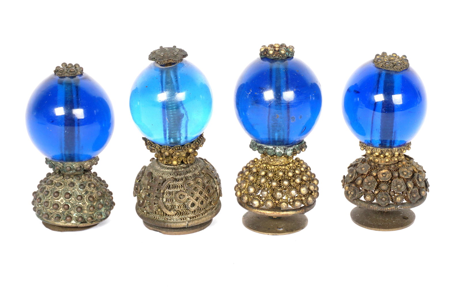 Four Chinese Qing Third Rank Hat Finials: An assembled collection of four, each with transparent blue Peking glass globes, assorted design pierced bases, largest measures 2.5" h., smallest 2.25".