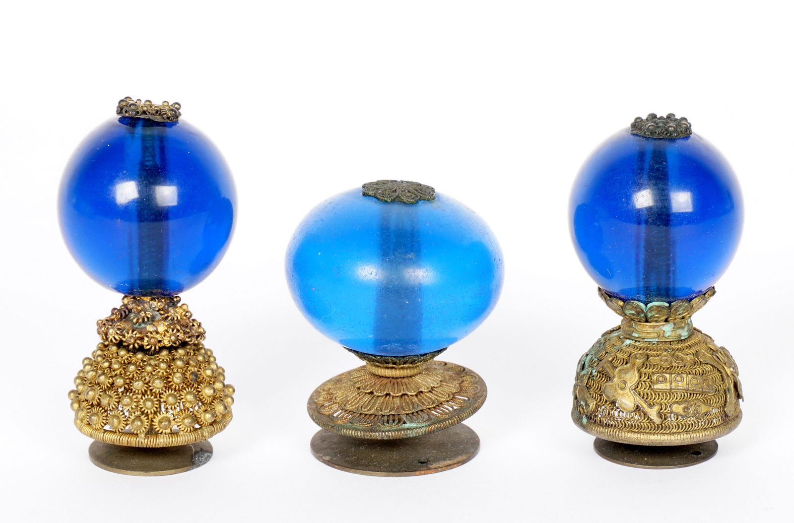 Three Chinese Qing Third Rank Hat Finials: An assembled collection of three, each with transparent blue Peking glass globes, assorted design pierced bases, largest measures 2.5" h., smallest 2" h. Condition: The smallest has chip to glass, one