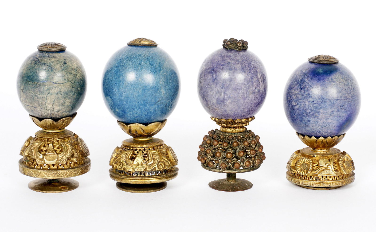 Four Chinese Qing Fourth Rank Hat Finials.: An assembled collection of four, each with variegated blue stone globes, assorted design pierced bases, largest measures 2.5" h., smallest 2.25" h.