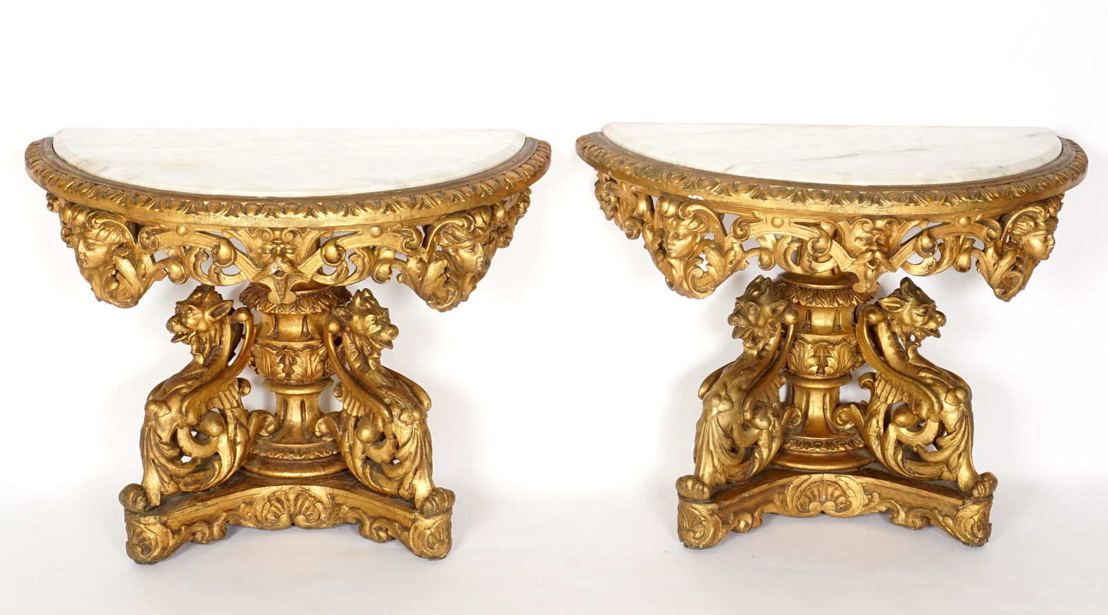 Pair Italian Carved Gilt Wood Demilune Console Tables: Most likely Italian, inset demilune marble top, bordered by carved egg and dart border, open work foliate scroll and masqueron apron, figural dragon supports, splayed legs. Overall 29.75" h. x 40.5" x