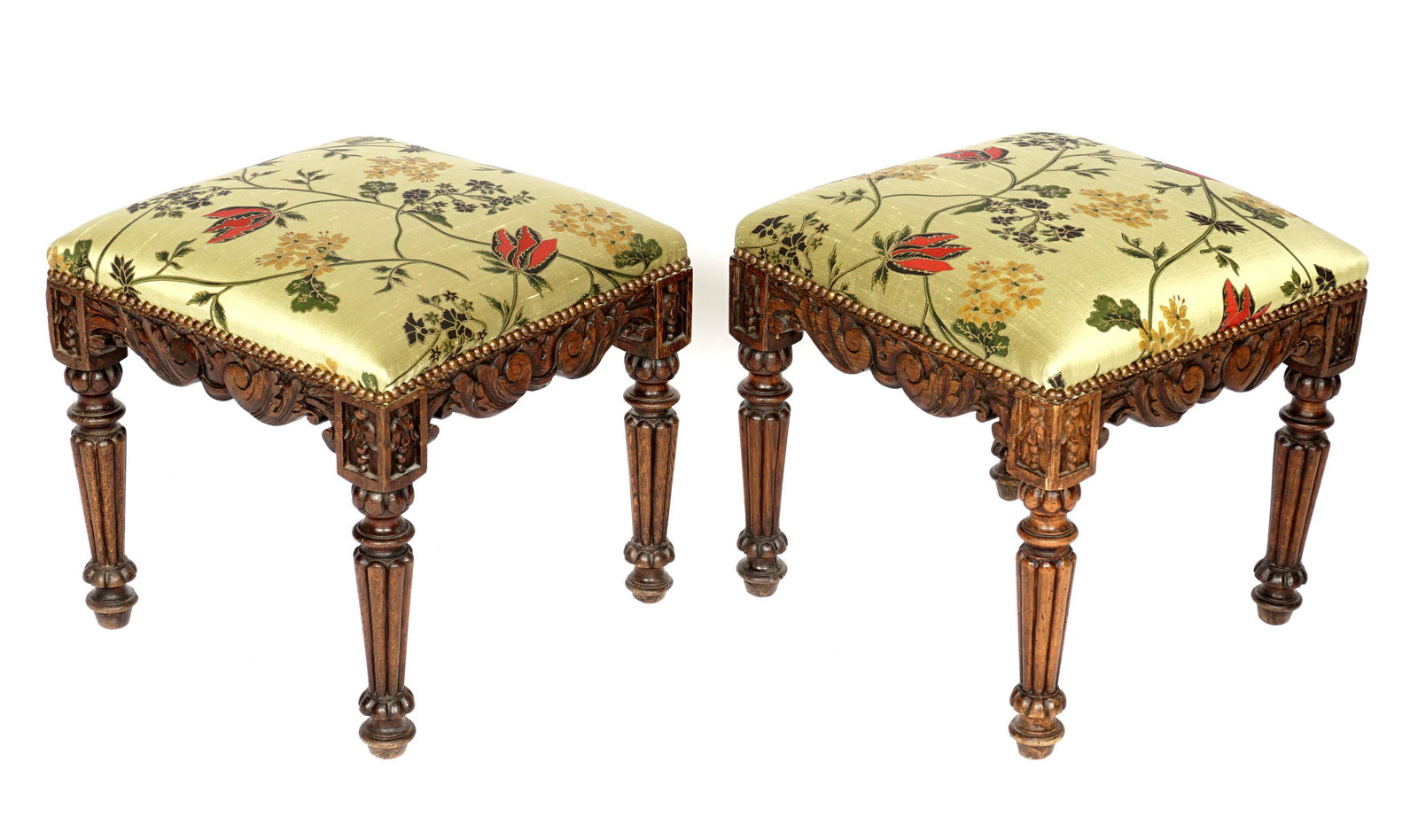 Pair Carved William IV Silk Upholstered Stools: Carved foliate scroll oak apron, bellflowers at corners, turned and fluted legs. Silk floral pattern upholstery. Overall 17" h. x 17.5" x 17.5". Condition: Wear to silk.