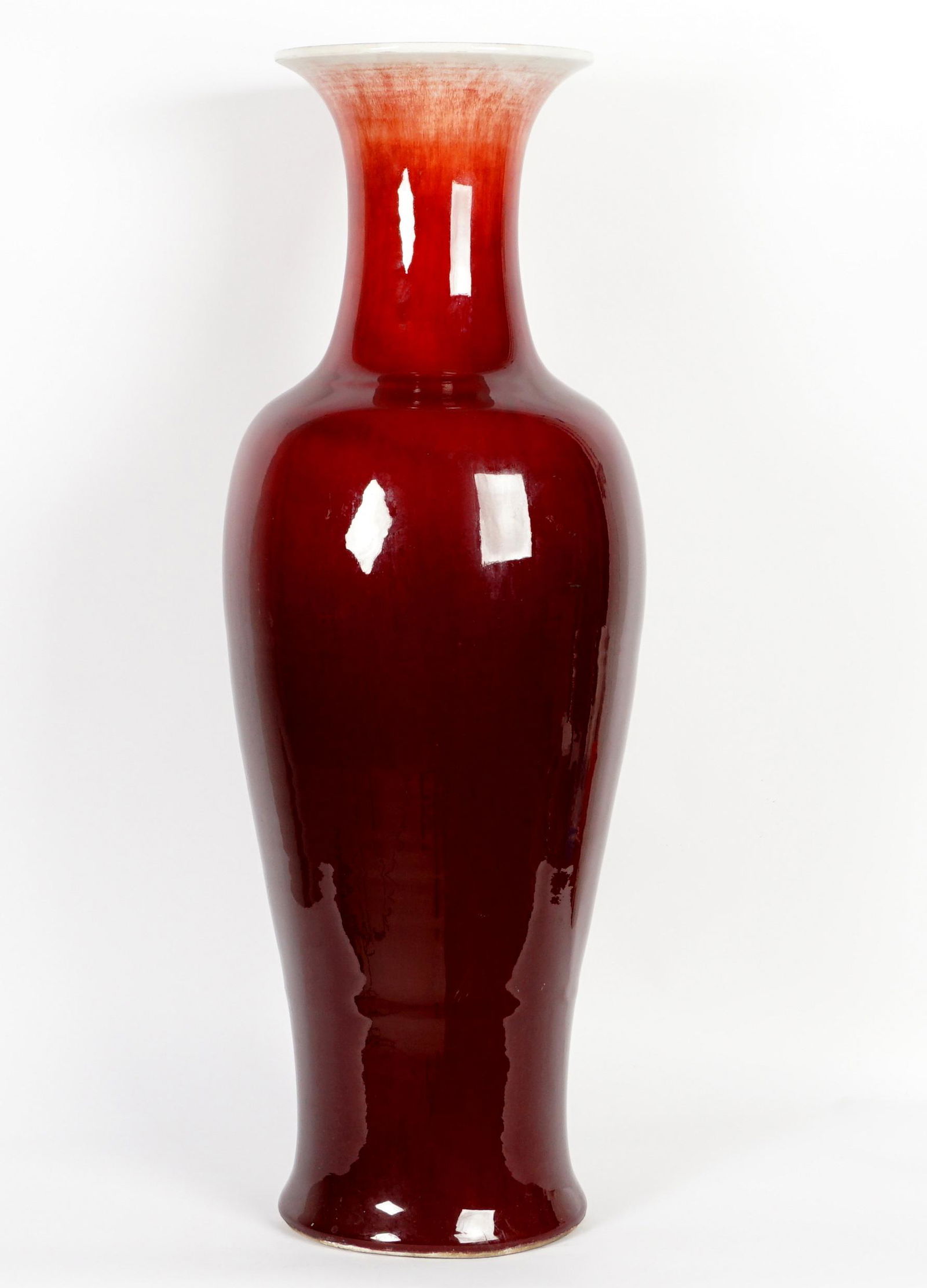 Large Chinese Sang de Boeuf Floor Vase: Baluster form vase with cream crackle glaze graduating to deep oxblood at base, unglazed foot and base, overall 36.25" h. x 12.5" dia. Condition: Minor abrasions near foot.