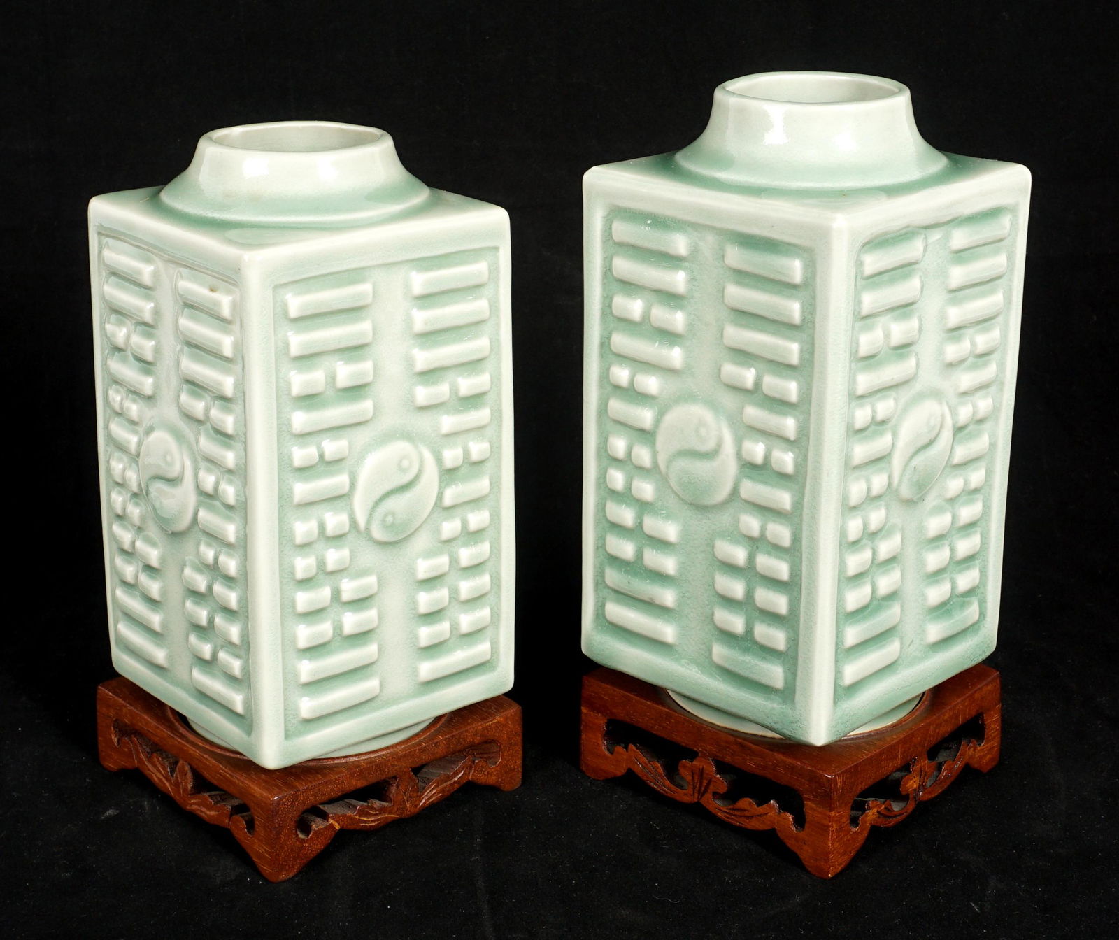 Pair Chinese Cong Form Celadon Vases: Square "Cong" form vases with raised decoration, center Yin Yang medallions on each side, tapered rim, recessed foot bearing impressed Kangxi markings. One vase slightly larger, 6.75" h. x 3.5" x 3.5"