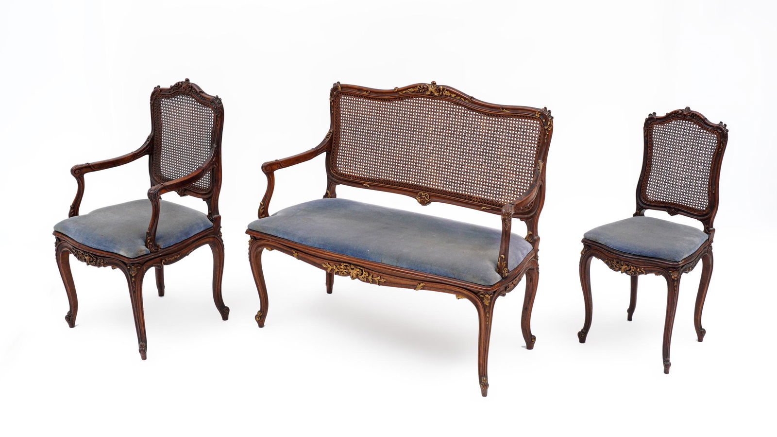 Three Piece Caned Back Parlor Set: Louis XV style set comprising of settee, arm chair, and side chair. Serpentine carved and shaped top rail, caned backs, shaped arms and supports. Conforming skirt and legs, blue velvet upholstery. Set