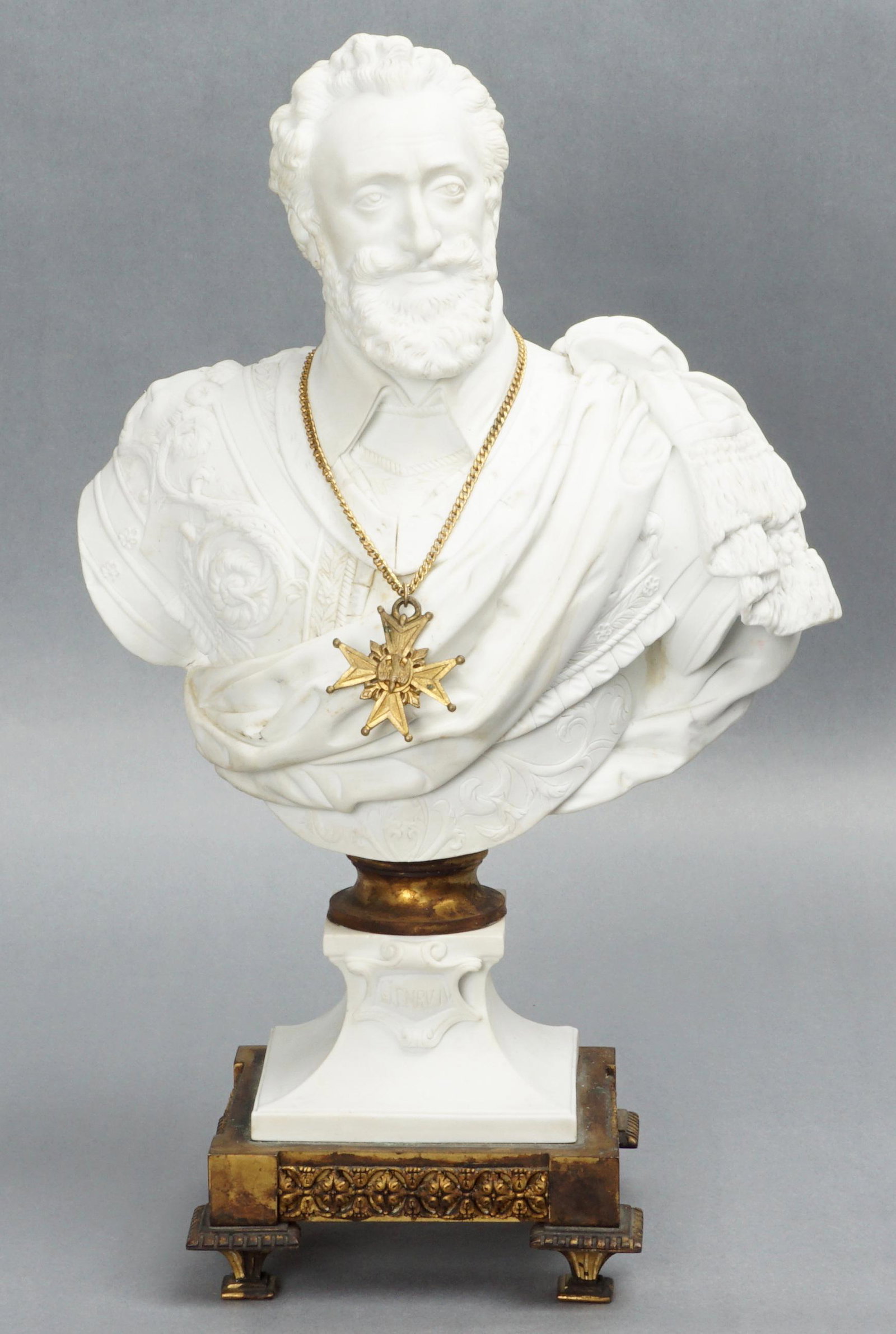 19th Century Sevres Parian Bisque Henry IV Bust: Porcelain bust of Henry IV with gold toned chain and cross, gold toned metal base and collar. Well marked on back with incised Sevres mark, signed and after Bachelier, overall 15" h. x 9.5" x 6. Condi