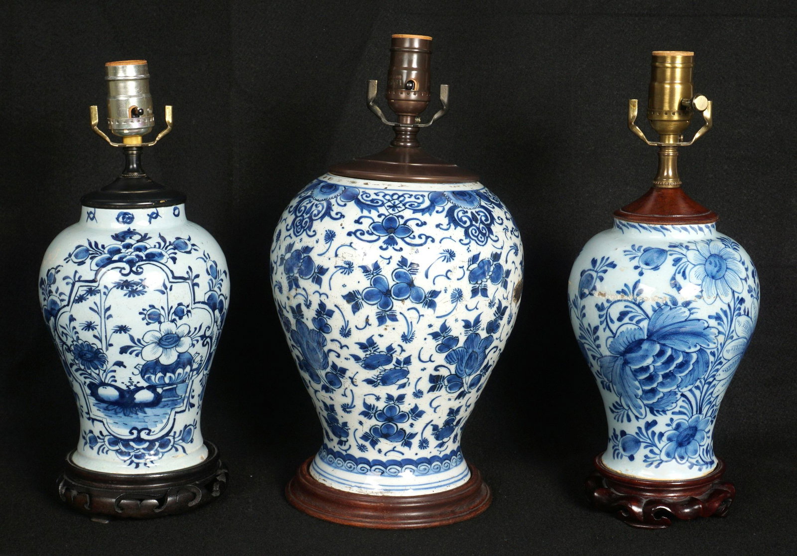 Three Delft Blue Lamps: An assembled collection of three Delft Blue jars mounted as lamps, wood bases, largest measures 14.5" h. x 7.5". Condition: Chips, cracks, crazing, and abrasions to be expected.