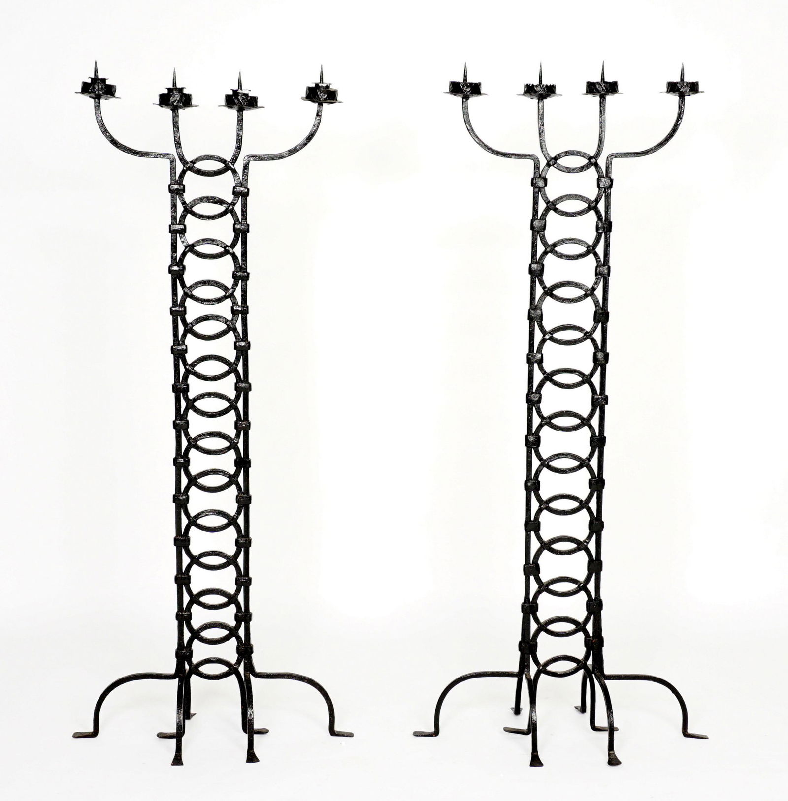 Pair Antique Wrought Iron Floor Candelabra: Heavy wrought iron floor candelabra / torchieres, each with four prickets, interlocking circles body, splayed feet. Overall 59.5" h. x 26.5" x 14.5".