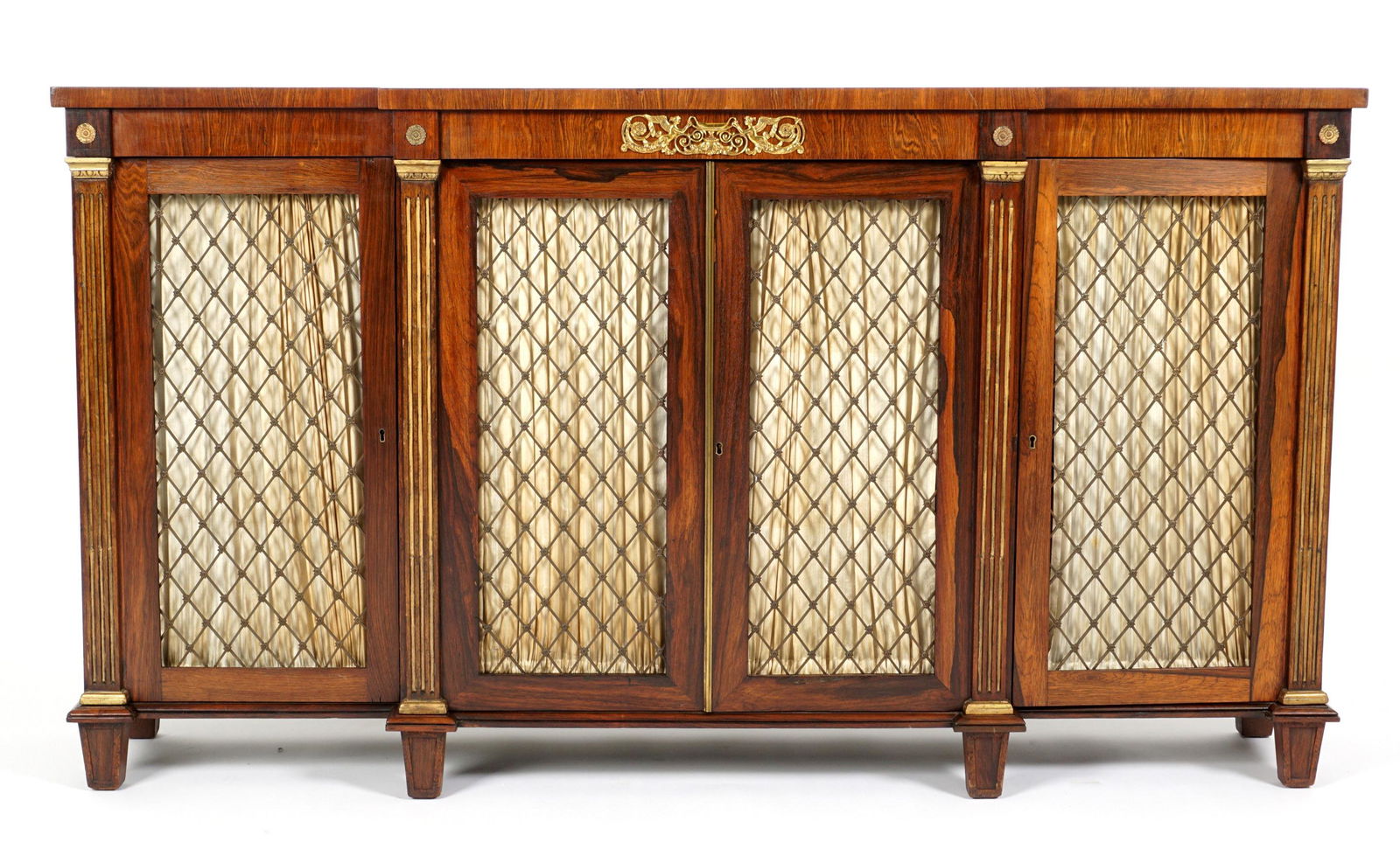 English James Winter Regency Rosewood Chiffonier: Rosewood case and top, step out center, applied ormolu decoration, fluted stiles, four wire mesh door fronts, fabric interior, stamped James Winter, 101 Wardour Street. Center two adjustable shelves,