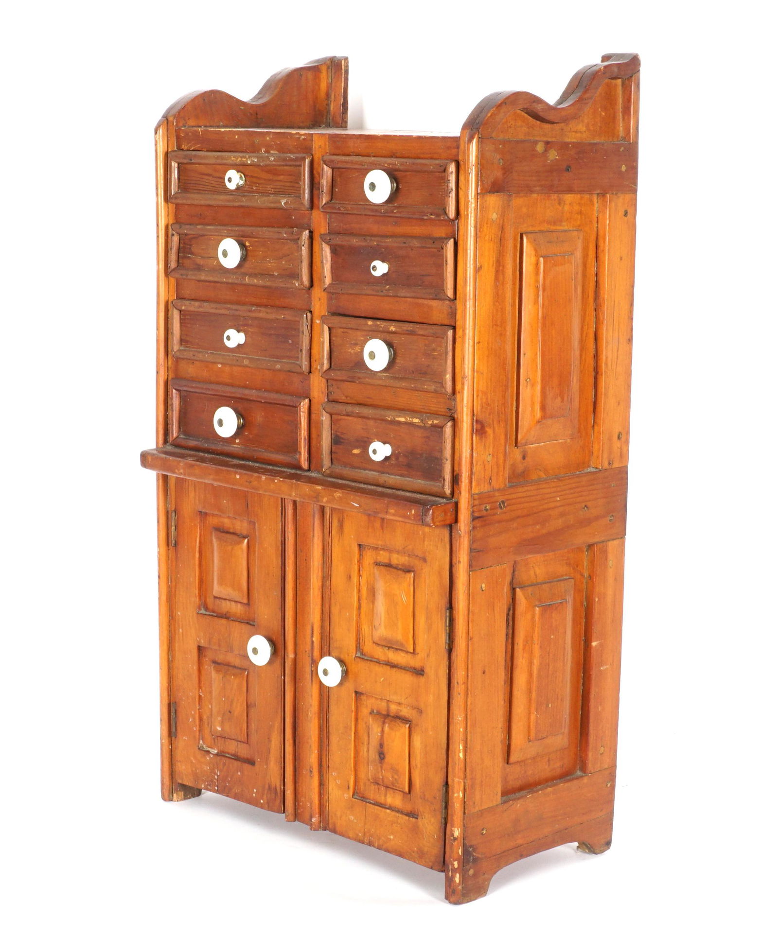 Antique Southern Pine Spice Chest: Shaped top gallery sides, eight drawers over two doors, rectangular decorated side panels, overall 31.75" h. x 17.75" x 10". Condition: Scratches, gouges, and wear.