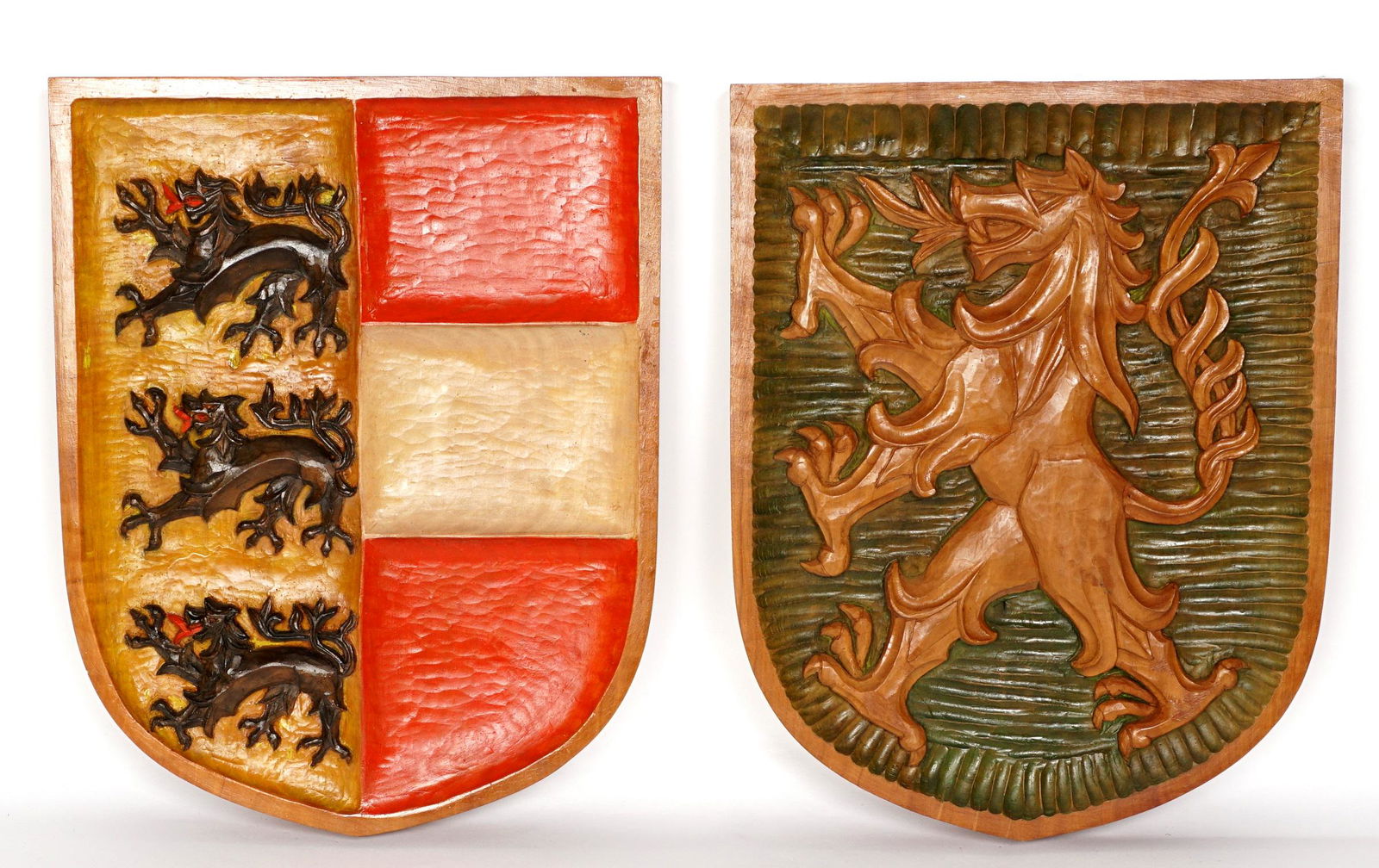 Pair Large Polychrome Carved Coat of Arms Plaques: Heraldic shield wall plaques, one with rampant lion on green ground, the other with three lions left, red and white stripes right, 20" x 15.75".