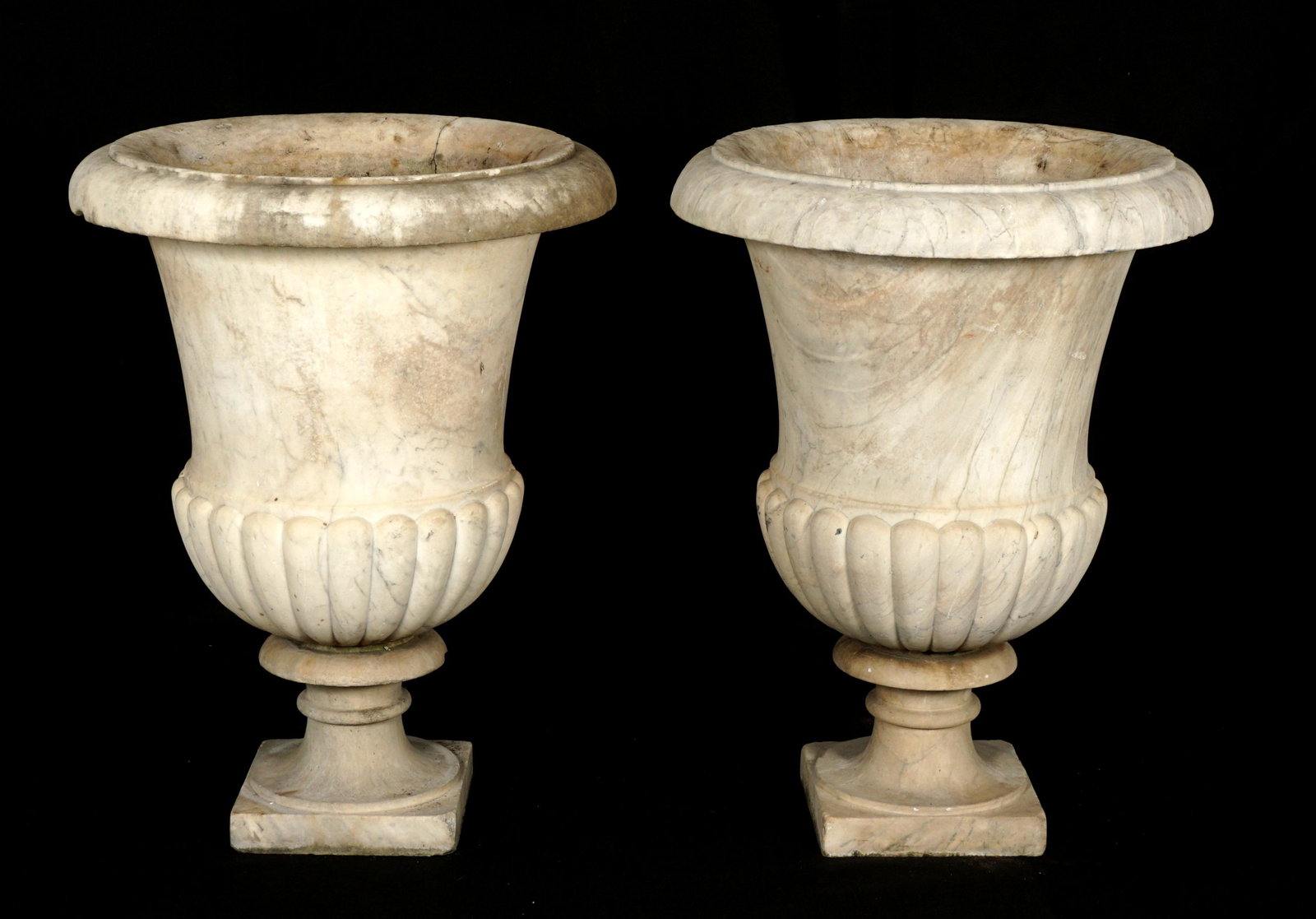 Pair of Marble Outdoor Garden Urns: Pair large marble garden urns, rolled lips, fluted bottoms, on turned column bases. Overall 32.75" h. x 25" dia. Condition: Both with chips and obvious signs of weathering. One with significant repair