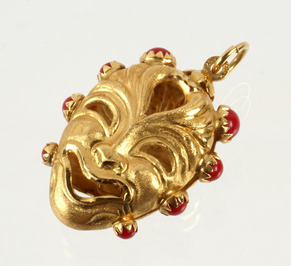 18k Italian Gold and Coral Mask Pendant: 14k yellow gold double sided Tragedy and Comedy mask pendant, eight coral cabochons, marked K18 Italy, 1 3/8" x 1". Approx. 8 grams inclusive.