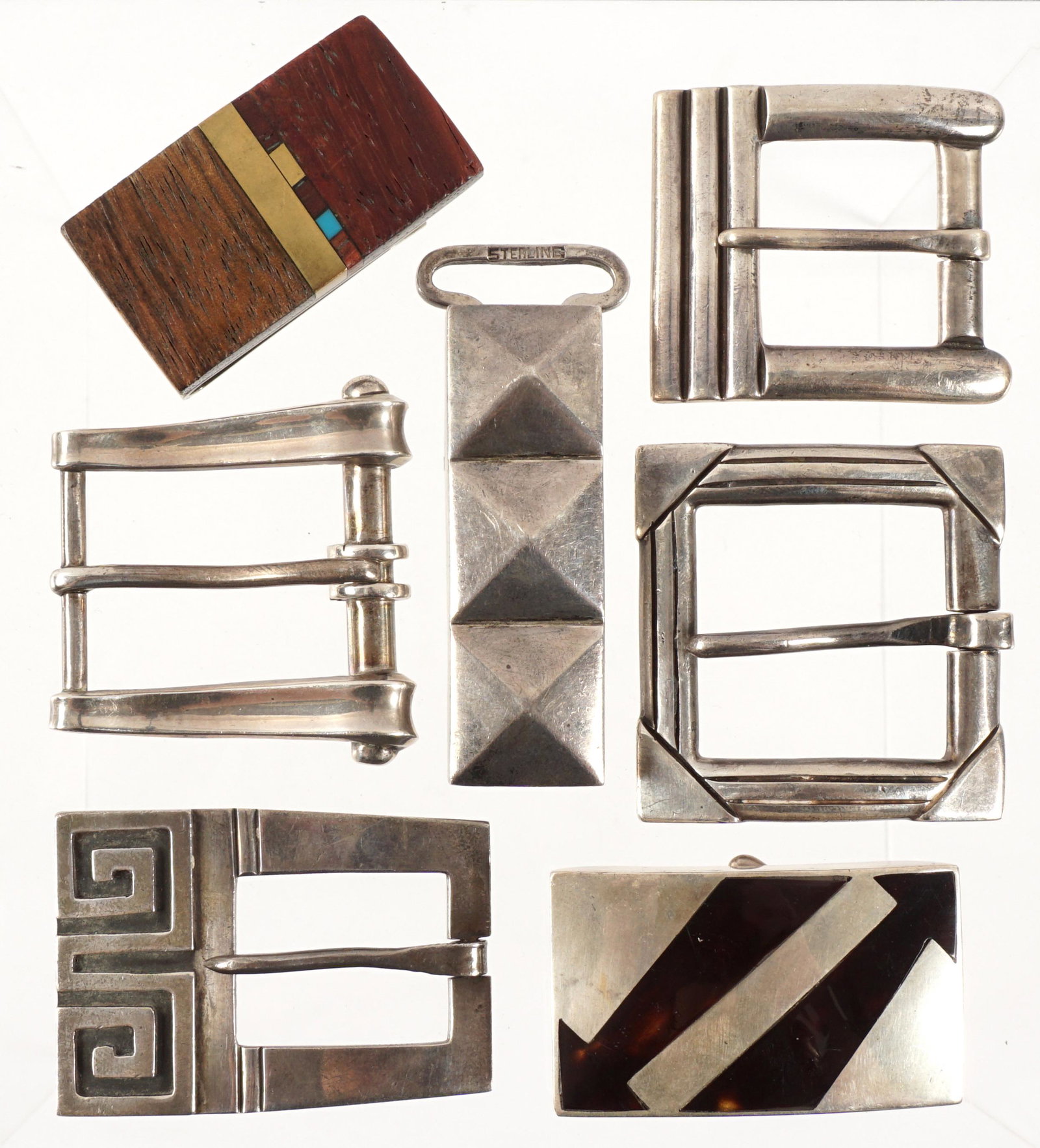 Six Mexican Sterling Buckles and a Money Clip: An assembled collection of seven pieces total. To include six belt buckles, makers to include Hector Aguilar, Victoria, William Spratling, Miguel Melendez, and unknown. Sold with wood, brass, and turq