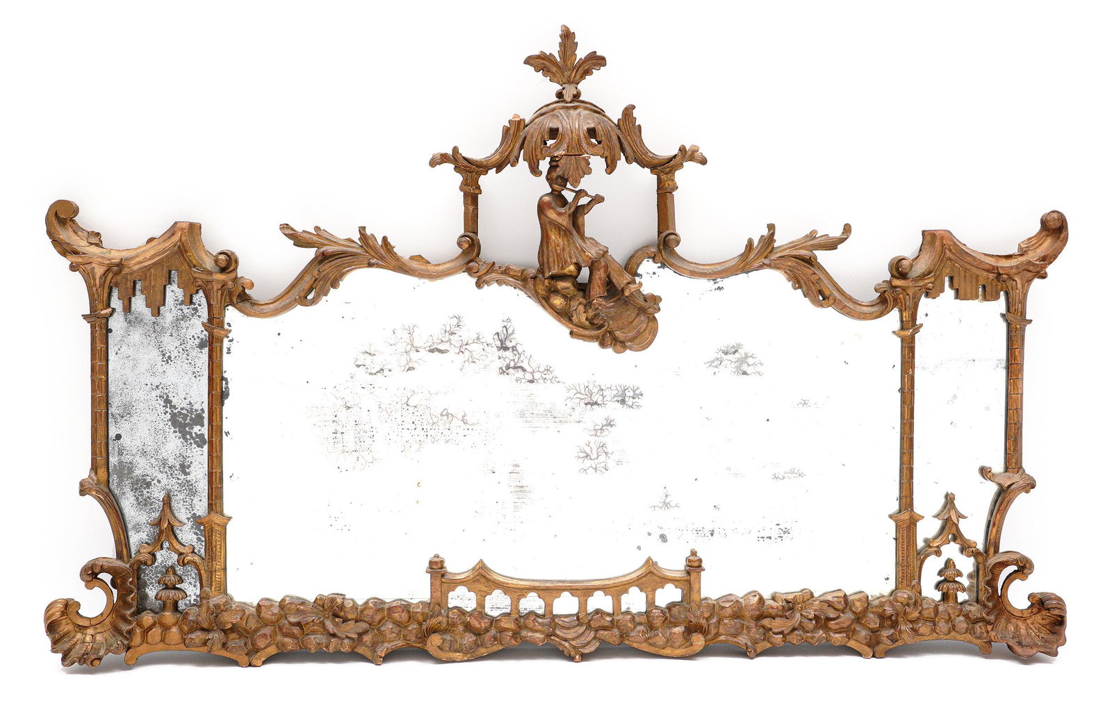 18th/19th C. Chinese Chippendale Gilt Wood Mirror: Ornate carved gilt wood frame, center crest with foliate pagoda over figure playing a flute, foliate scroll top, half column carved side trim and mirror separators, lower floral design with shell ends