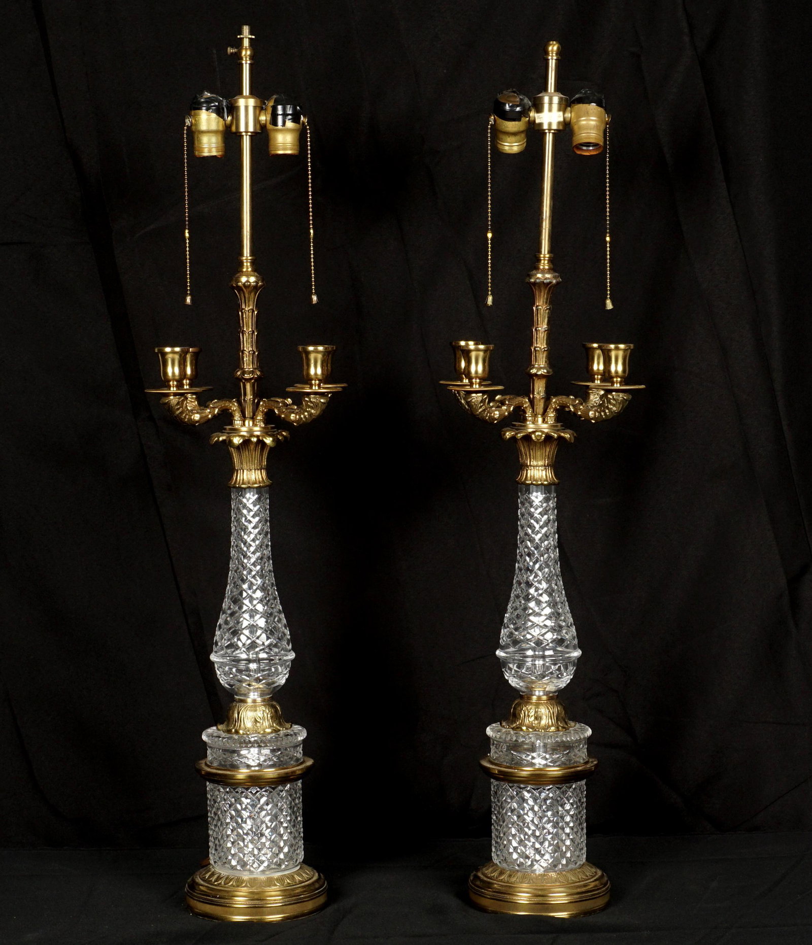 Pair Warren Kessler Gilt Mounted Crystal Lamps: Pair gilt bronze mounted table lamps, double socket fixture over four candle arms, cut crystal body. Warren Kessler label at top. Overall 36.5" h. x 10.5". Missing finial.