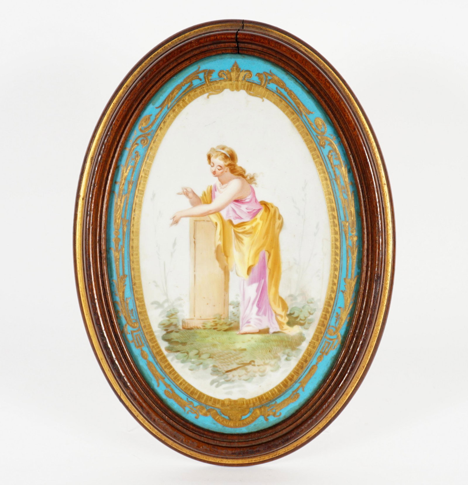 Insouciance Sevres Style Porcelain Wall Plaque: Oval porcelain plaque, hand painted with image of woman leaning on a pedestal, blue border, gilt foliate scroll accents, titled "Insouciance" on bottom and verso, no markings, plaque measures 11" x 7.