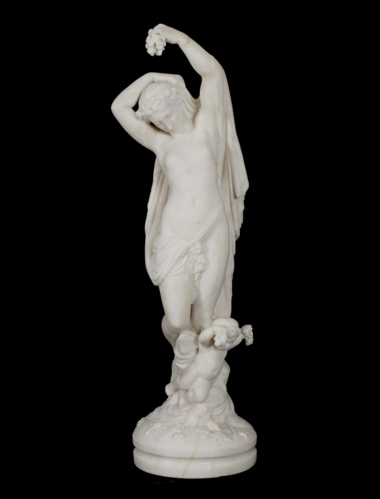 Carved Marble Semi Nude Woman with Cherub: Neoclassical semi nude maiden holding flowers in one hand, flowing robes in other, cherub holding flowers at her feet, no visible signature, 27" x 8". Condition: Repair to arm, abrasion on stomach.