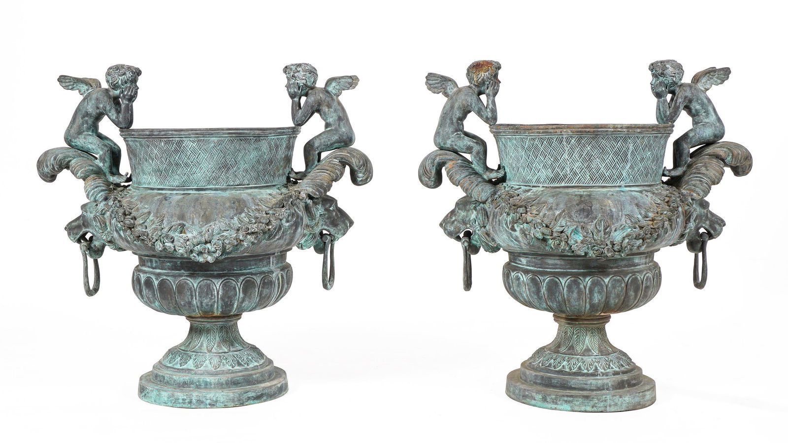Pair Cherub and Lion Head Bronze Garden Urns: Each bronze urn with figural cherub finials over lion head handles, footed base, overall 30.75" h. x 31.5". Condition: Obvious signs of weathering. From the estate of a prominent lawyer from New Roche