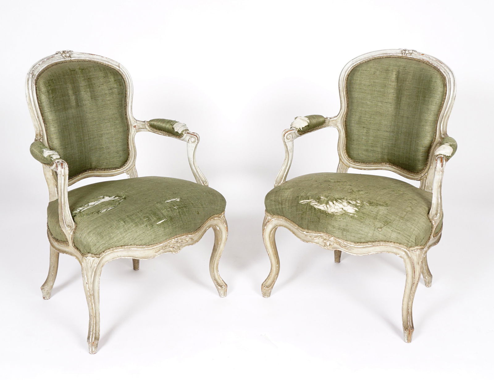 Pr Green French Louis XV Fauteuil Arm Chairs: 18th Century, carved and painted frames, shield backs, floral crest, shaped arms, fluted hand holds, conforming skirt, cabriole legs, green upholstery in need of repair. Overall 34.25" h. x 24" x 24".