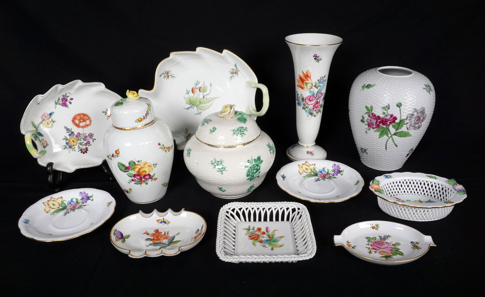 12 Pieces Assorted Herend Porcelain Accessories: An assorted collection of 12 pieces total, various patterns, to include tall vase, ovoid vase, 2 covered jars, 2 saucers, 2 leaf form trays, 2 reticulated trays, 2 ashtrays. Tallest vase 9" h., smalle